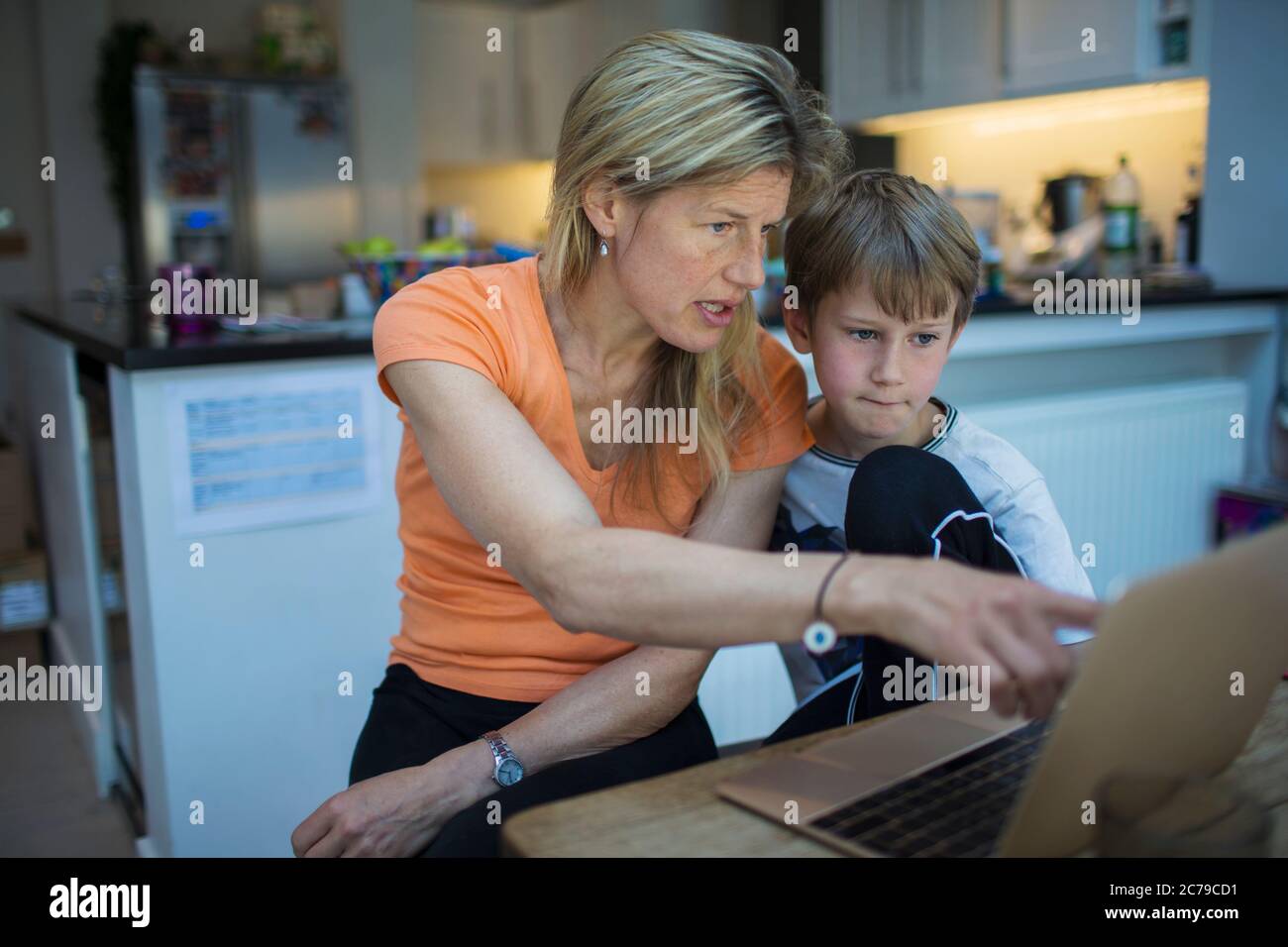 Mutter hilft Sohn mit Heimarbeit an Laptop Stockfoto