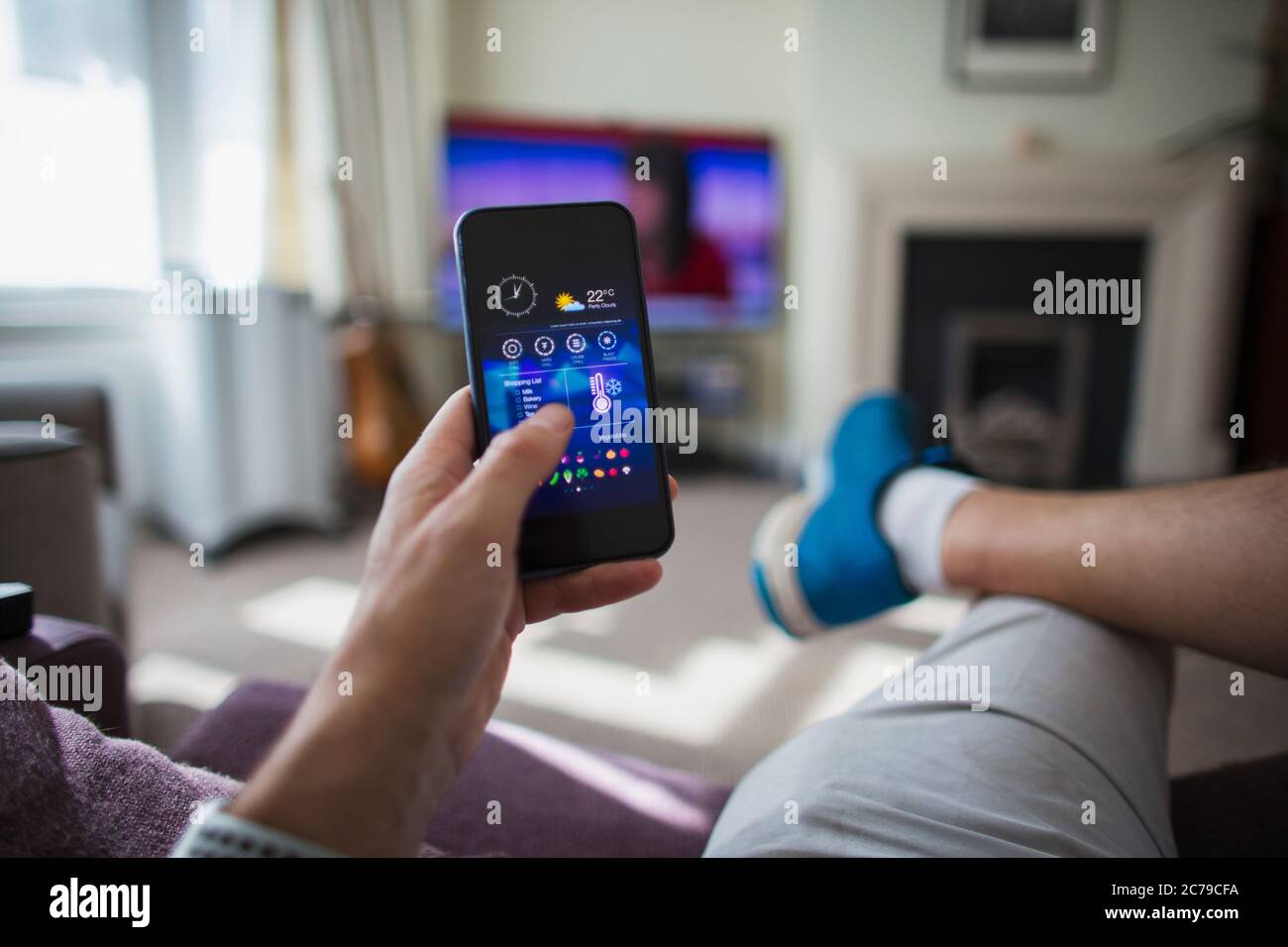 POV man Temperaturregelung auf Smartphone im Wohnzimmer Stockfoto