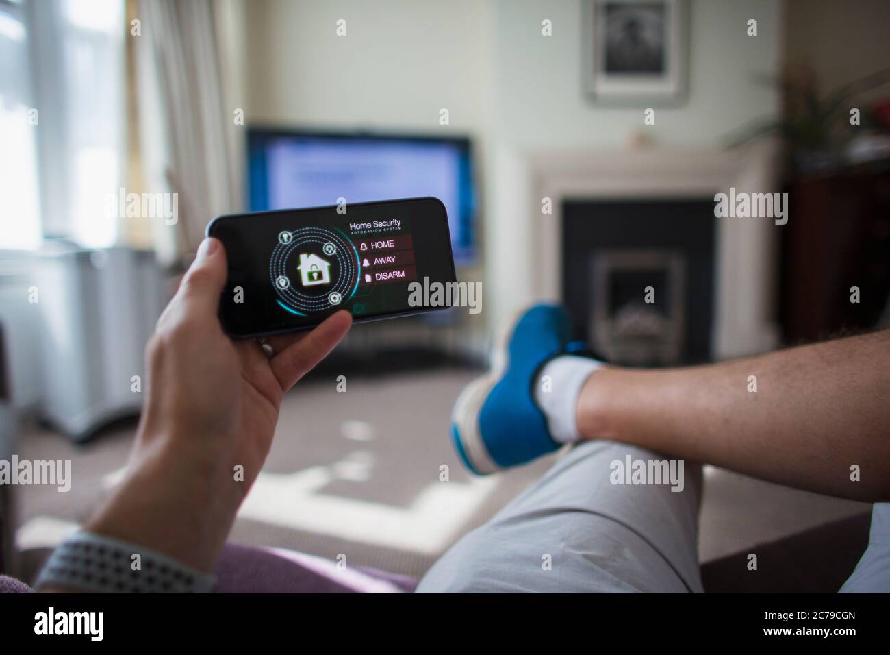 POV Mann Überprüfung der Sicherheit zu Hause auf Smartphone im Wohnzimmer Stockfoto