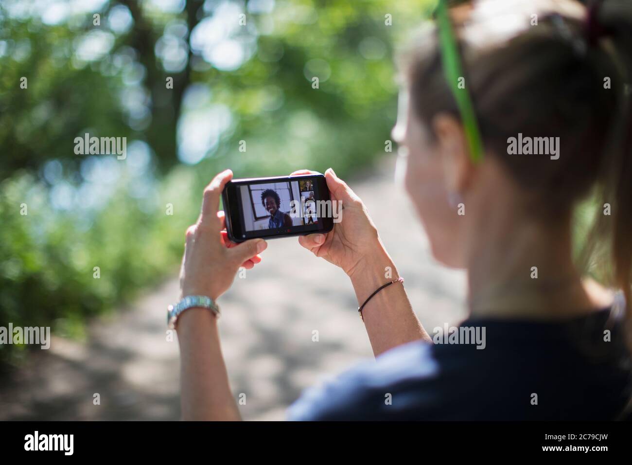 Frau Video chatten mit Freunden auf Smartphone-Bildschirm im sonnigen Park Stockfoto
