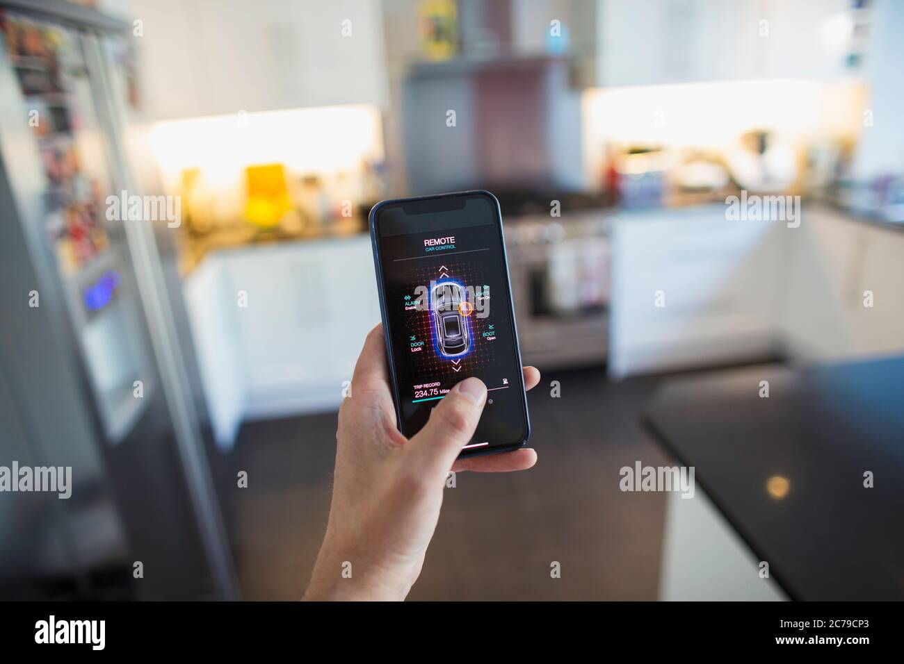 POV man sichert Autoalarm vom Smartphone-Bildschirm in der Küche Stockfoto
