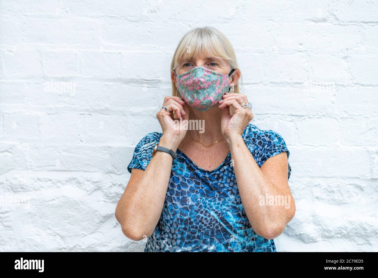 Frau trägt stilvolle, modische Coronavirus Gesichtsmaske während Covid-19 Pandemie, bereit für Ende der Sperre gehen nach draußen in der Öffentlichkeit. Weißer Hintergrund Stockfoto