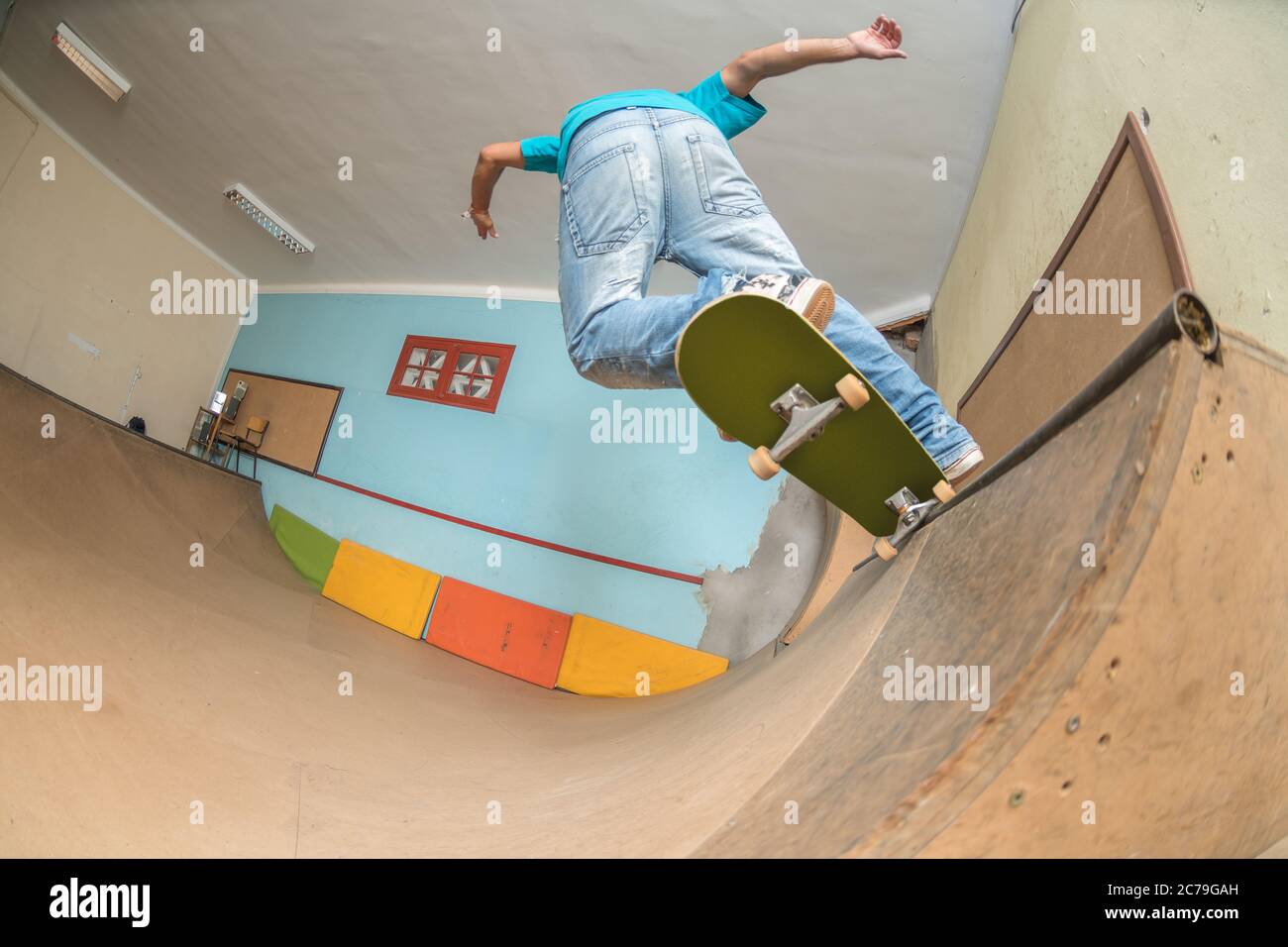 Skateboarder, der einen Trick auf der Mini-Rampe im Indoor-Skatepark macht. Stockfoto