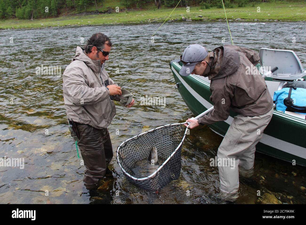 Eine Taimenforelle landete in einem Netz von zwei Angler neben einem Floß in der Mongolei, Moron, Mongolei - 14. Juli 2014 Stockfoto