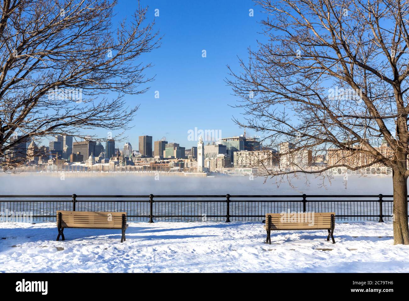 Blick über den St. Lawrence River bis ins Zentrum von Montreal. Winter mit Schnee auf dem Boden und Nebel steigt aus dem gefrorenen Wasser. Stadtbild eingerahmt Stockfoto