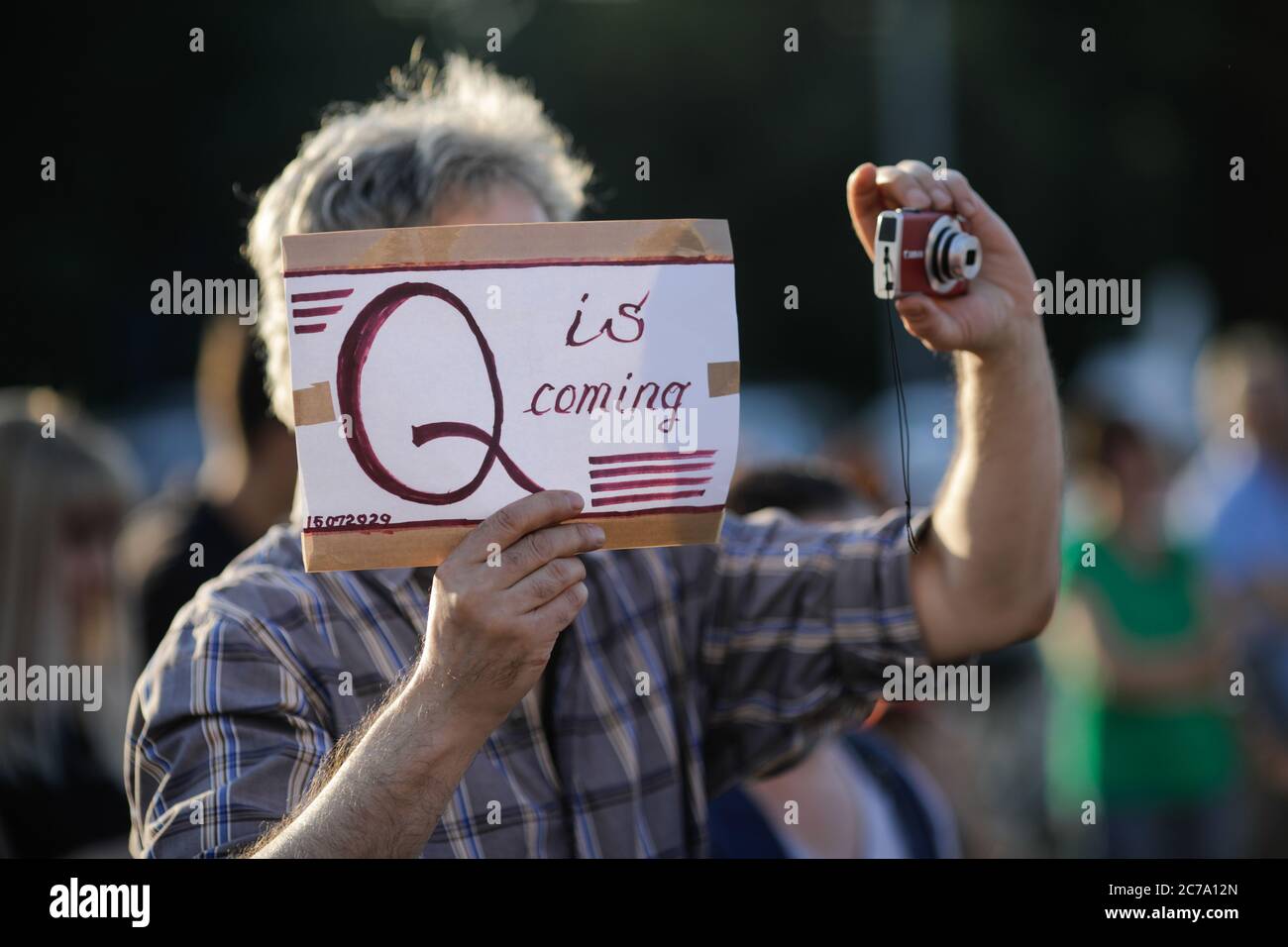 Bukarest / Rumänien - 15. Juli 2020: Ein Mann nimmt an einem Protest Teil und zeigt eine Botschaft von Qanon auf einer Pappe. Stockfoto