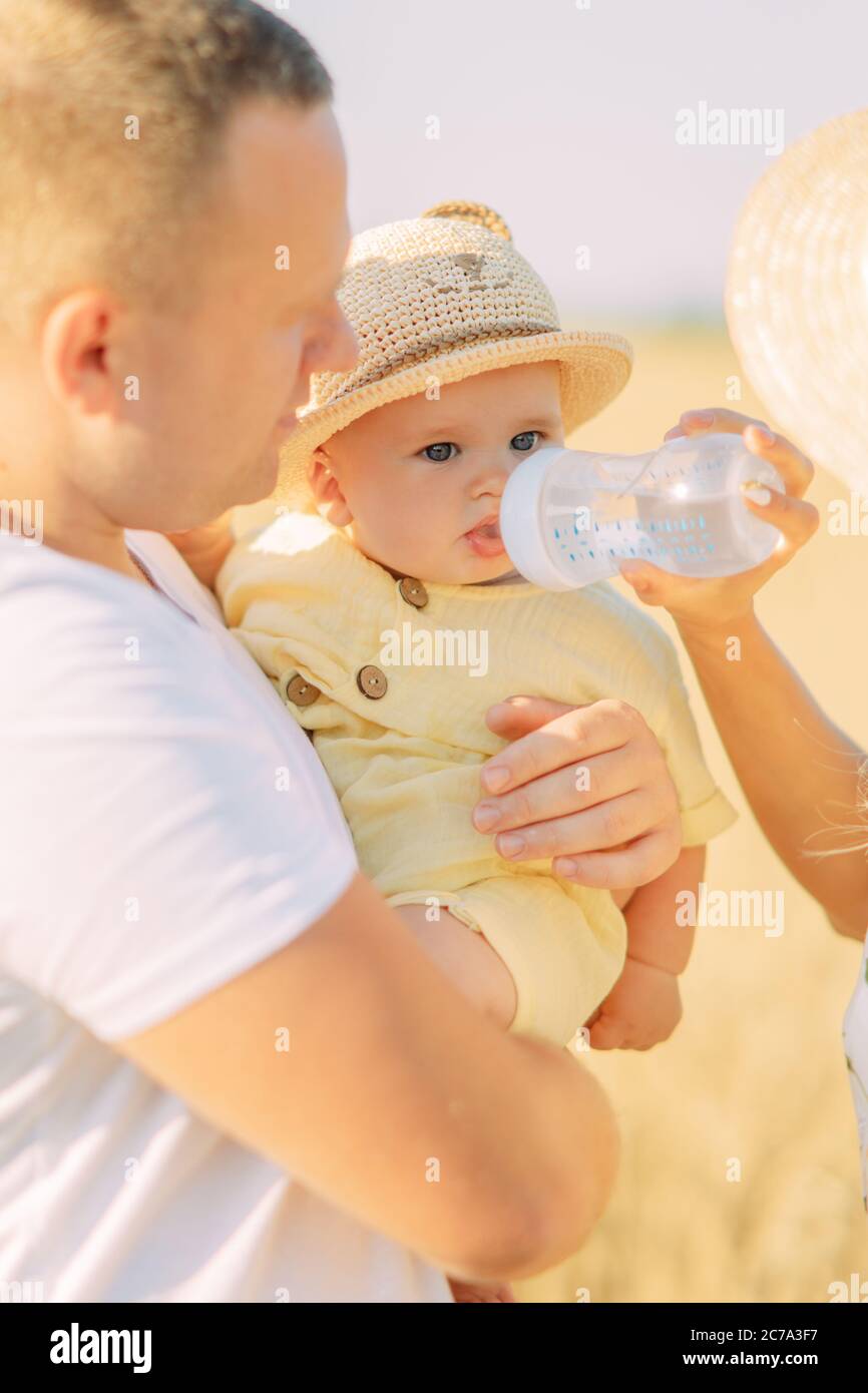 Junge Eltern füttern ihr Baby mit Milch aus der Flasche während des Ausflugs. Stockfoto