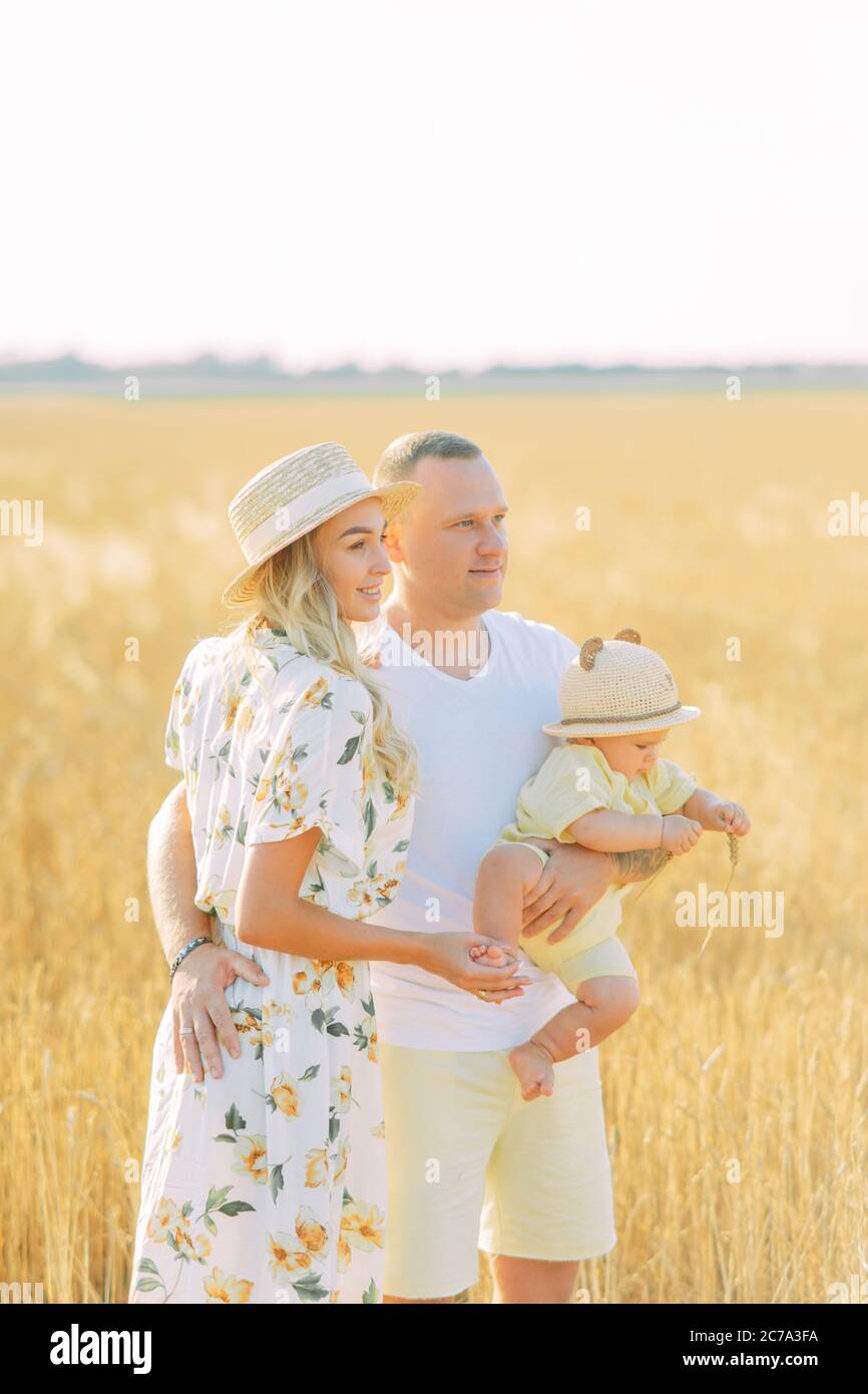 Glückliche junge Familie geht in gelben Weizenfeld mit Baby. Stockfoto