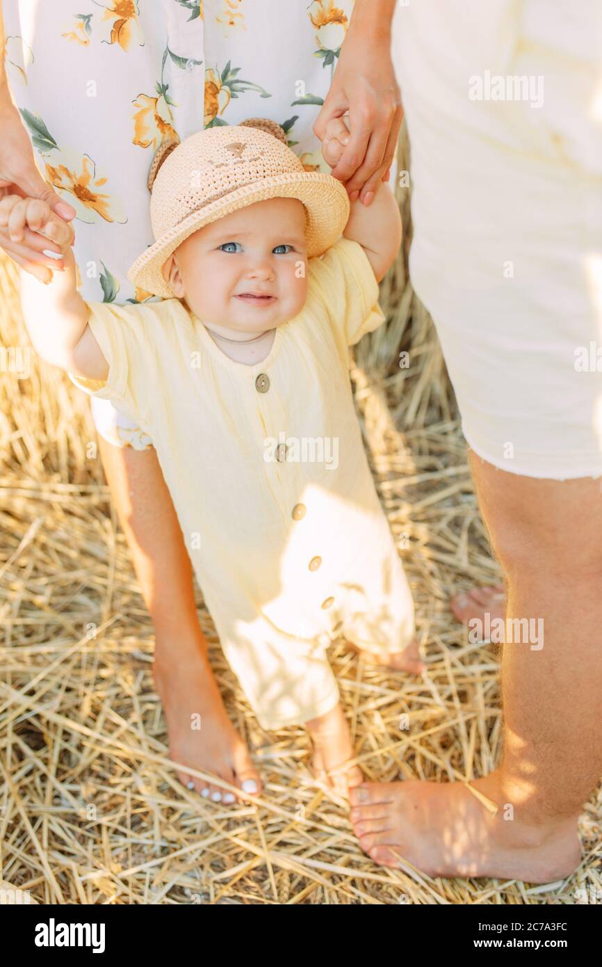 Junge Eltern führen und halten ihr Baby mit den Händen im gelben Weizenfeld. Stockfoto