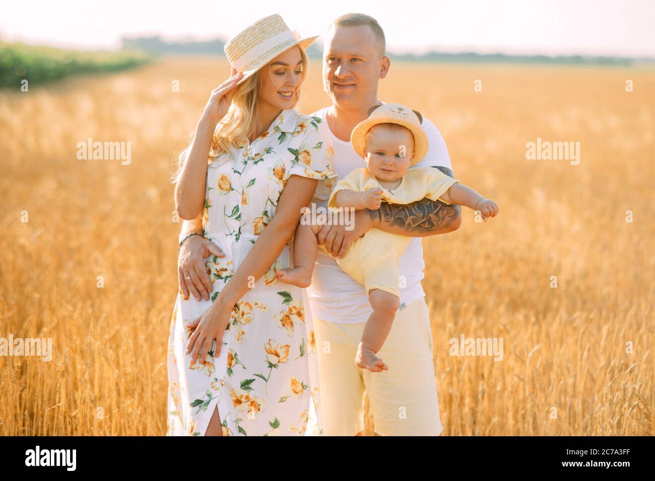 Glückliche junge Familie mit Baby Spaziergänge in gelben Weizenfeld. Stockfoto