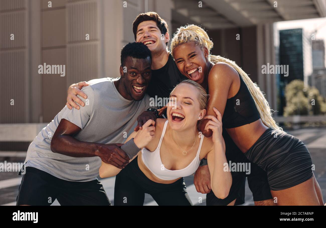 Multi ethnische Gruppe von jungen Frauen trainieren im Freien in der Stadt. Männer und Frauen in Sportkleidung stehen zusammen und lachen. Stockfoto