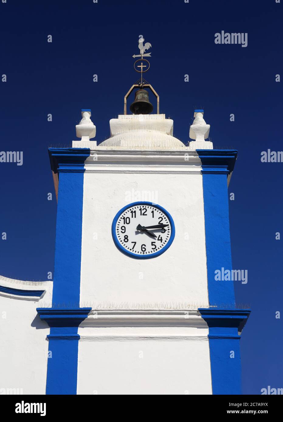 Portugal, Sines, Vila Nova de Milfontes. Unsere Dame der Gnade Kirche. Detail der weiß gewaschenen und blauen Fassade und Glockenturm gegen einen klaren blauen Himmel. Stockfoto