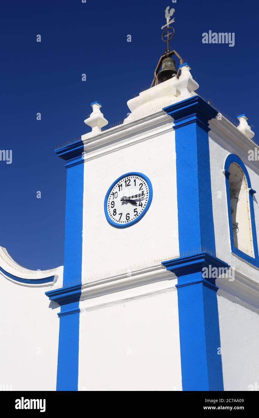 Portugal, Sines, Vila Nova de Milfontes. Unsere Dame der Gnade Kirche. Detail der weiß gewaschenen und blauen Fassade und Glockenturm gegen einen klaren blauen Himmel. Stockfoto