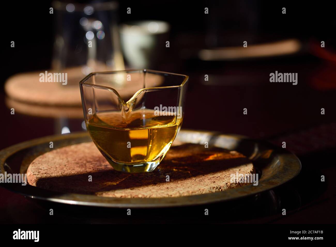 Auf einem dunklen Tisch ist eine kleine Glas Teekanne mit Bernstein Tee in ihm Stockfoto