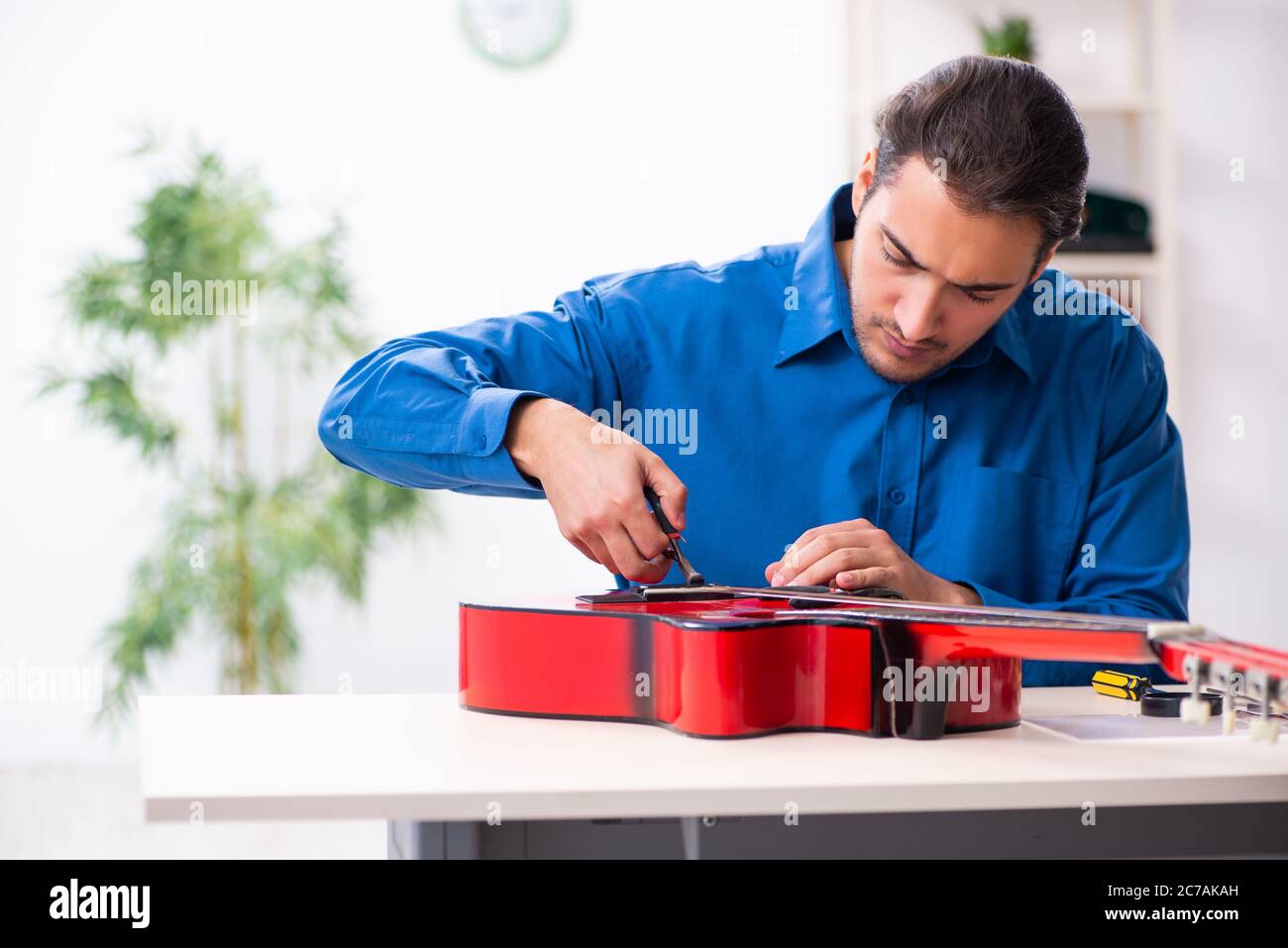 Junger Mann Reparatur der Gitarre Stockfoto