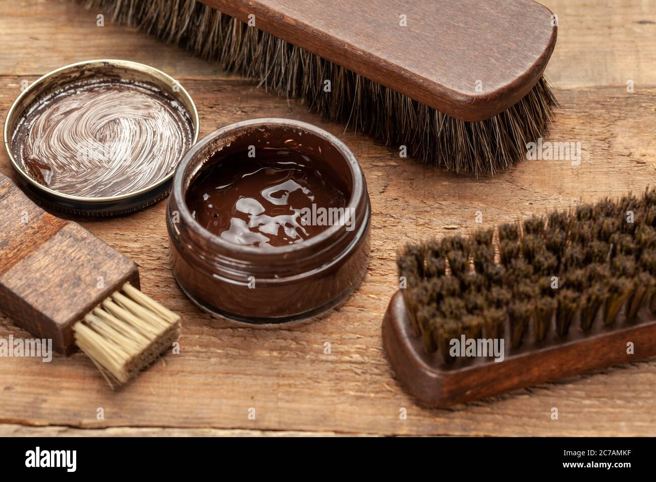 Bürste für Schuhe. Schuhe mit Bürsten reinigen und polieren. Schuhcreme und Pinsel auf Holzhintergrund. Stockfoto