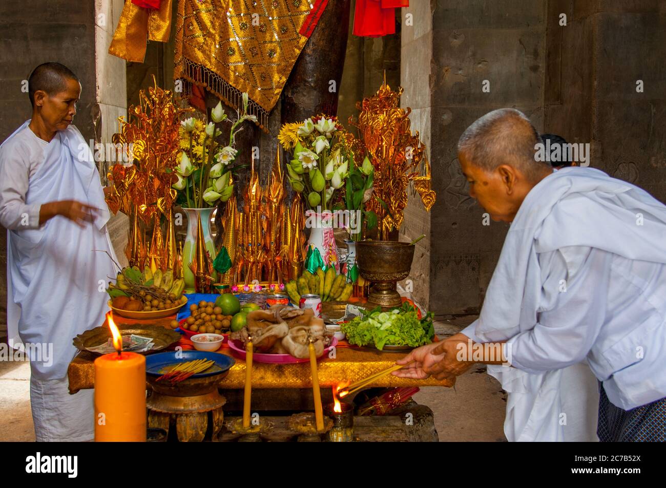 Eine buddhistische Nonne ordnet Opfergaben an der Basis einer dekorierten Statue von Herrn Vishnu, einem Hindu-gott, dem Obersten Gott des Vaishnavismus (einer der drei Stockfoto