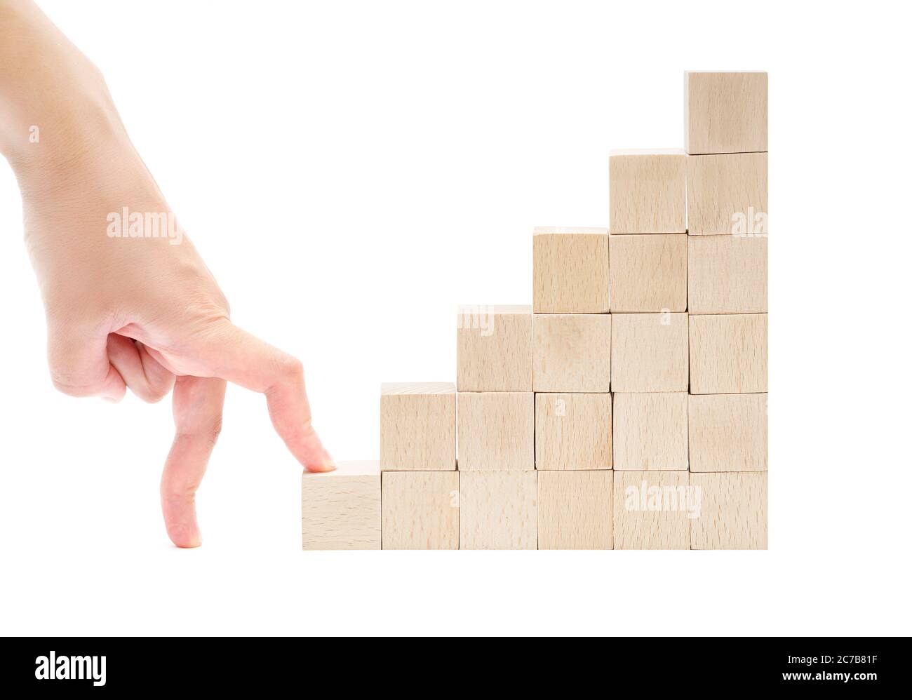 Die Handfinger beginnen die Treppe aus Holzspielzeugblöcken auf weißem Hintergrund zu klettern. Erster Schritt auf dem Karriereleiter-Konzept. Stockfoto