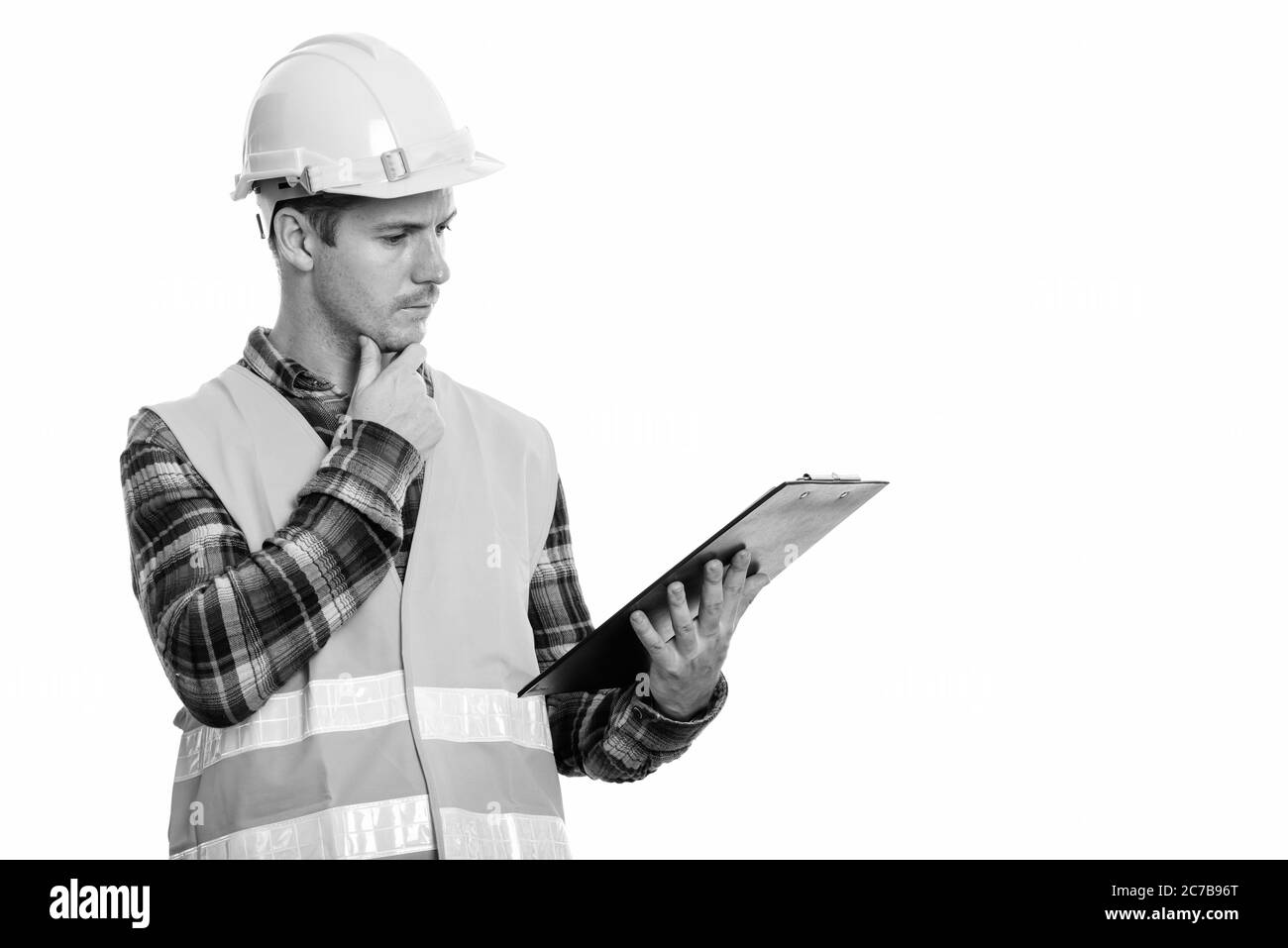 Studio-Aufnahme des Menschen Bauarbeiter Lesen auf Zwischenablage beim Denken Stockfoto