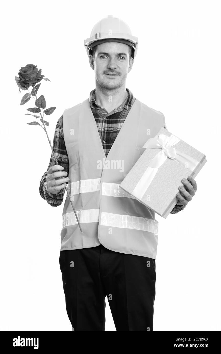 Glücklicher Mann Bauarbeiter lächelt, während halten rote Rose und Geschenkbox bereit für Valentinstag Stockfoto