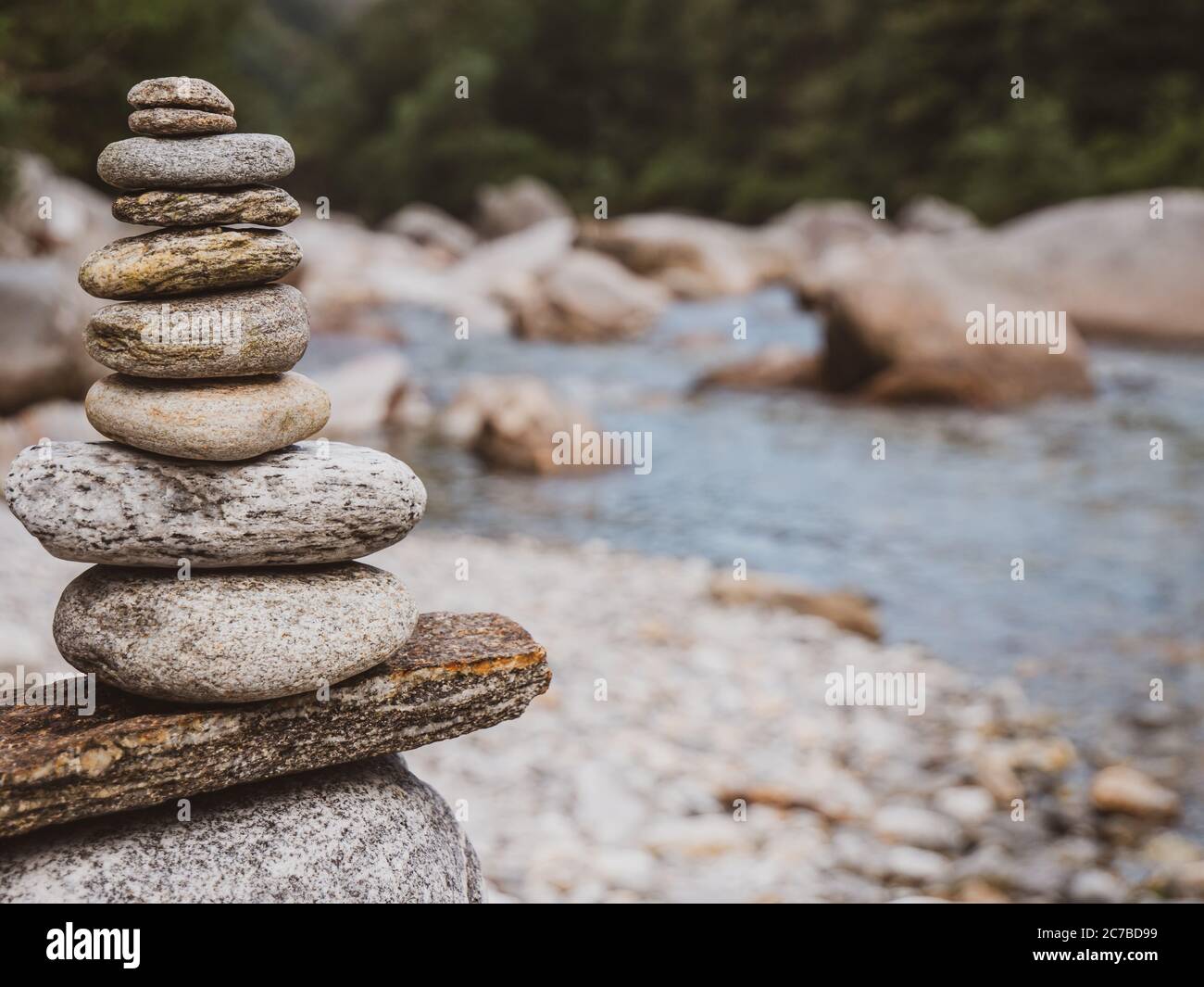 Nahaufnahme eines sorgfältig gebauten Felsenkairns am ruhigen Flussufer eines Alpenflusses in der Schweiz. Stockfoto
