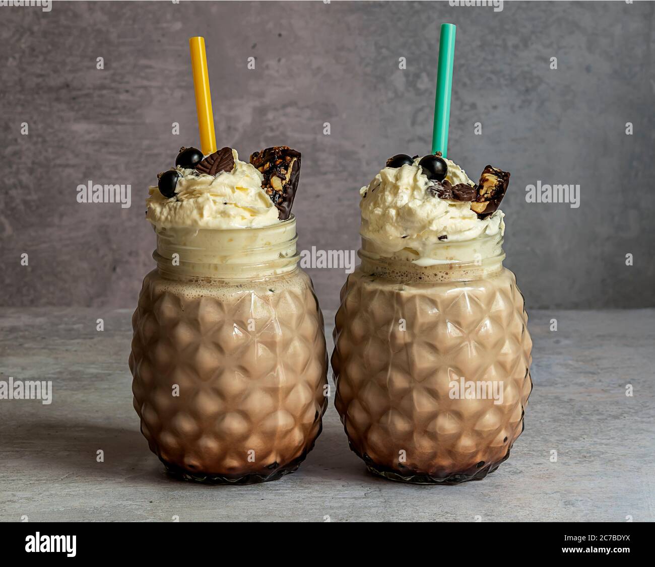 Schokoladenmilchshake mit Eis, Schlagsahne, Beeren, Keksen und Waffeln, serviert in einem Glas-Einmachglas. Stockfoto