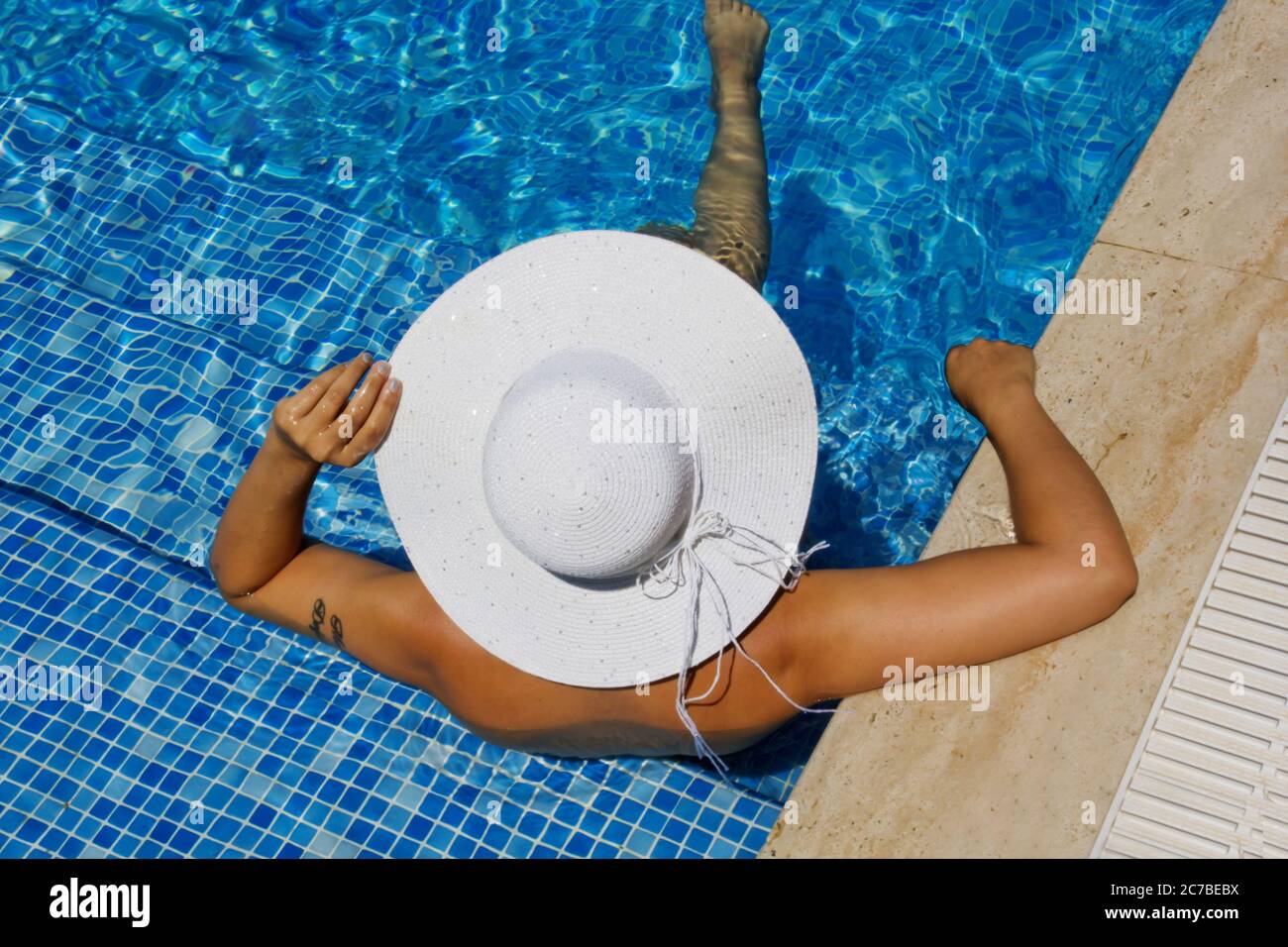 Junge Frau in einem weißen Hut entspannen im Pool Stockfoto