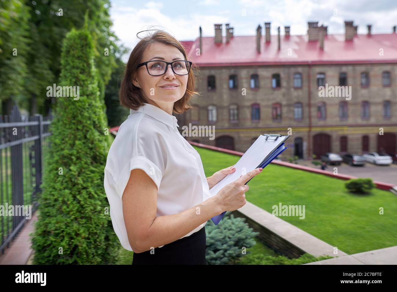 Porträt von selbstbewussten lächelnden Geschäftsfrau, Lehrerin, Beraterin mit Zwischenablage Papierdokumente Stockfoto