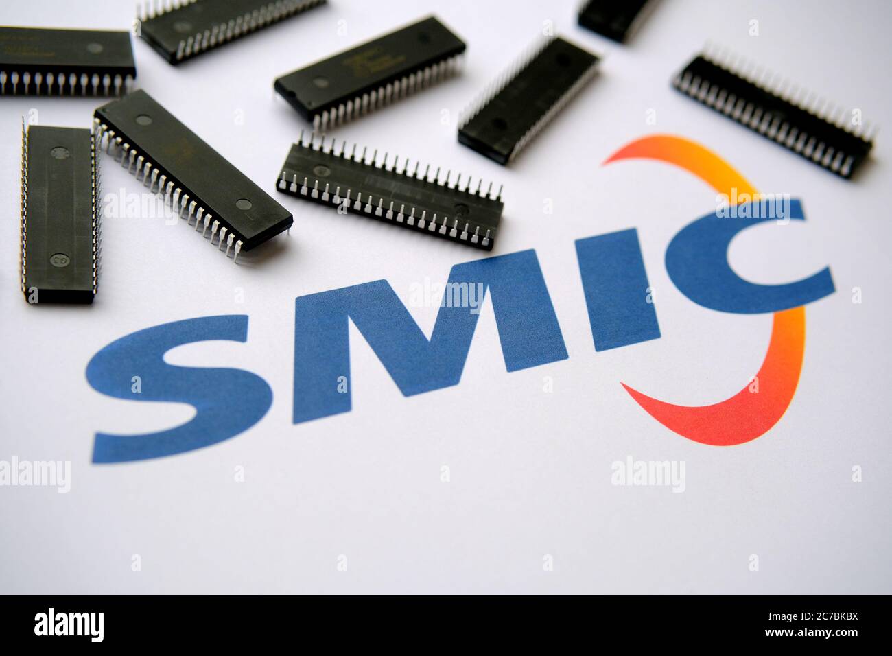 Stone / UK - 8. Juli 2020: SMIC-Logo auf dem Papierdokument und große Mikrochips, die herum platziert sind. Illustration für Hersteller von elektronischen Chips. Stockfoto