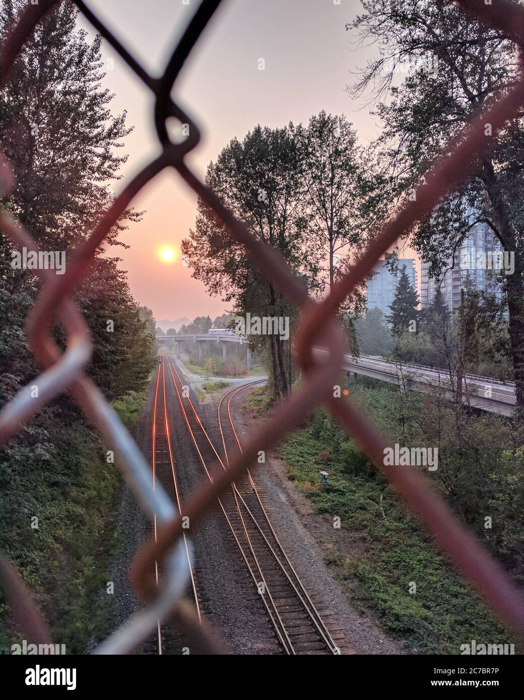 Vertikale Aufnahme durch einen Zaun einer Eisenbahn mit dem Sonnenuntergang sichtbar gemacht, British Columbia, Kanada Stockfoto