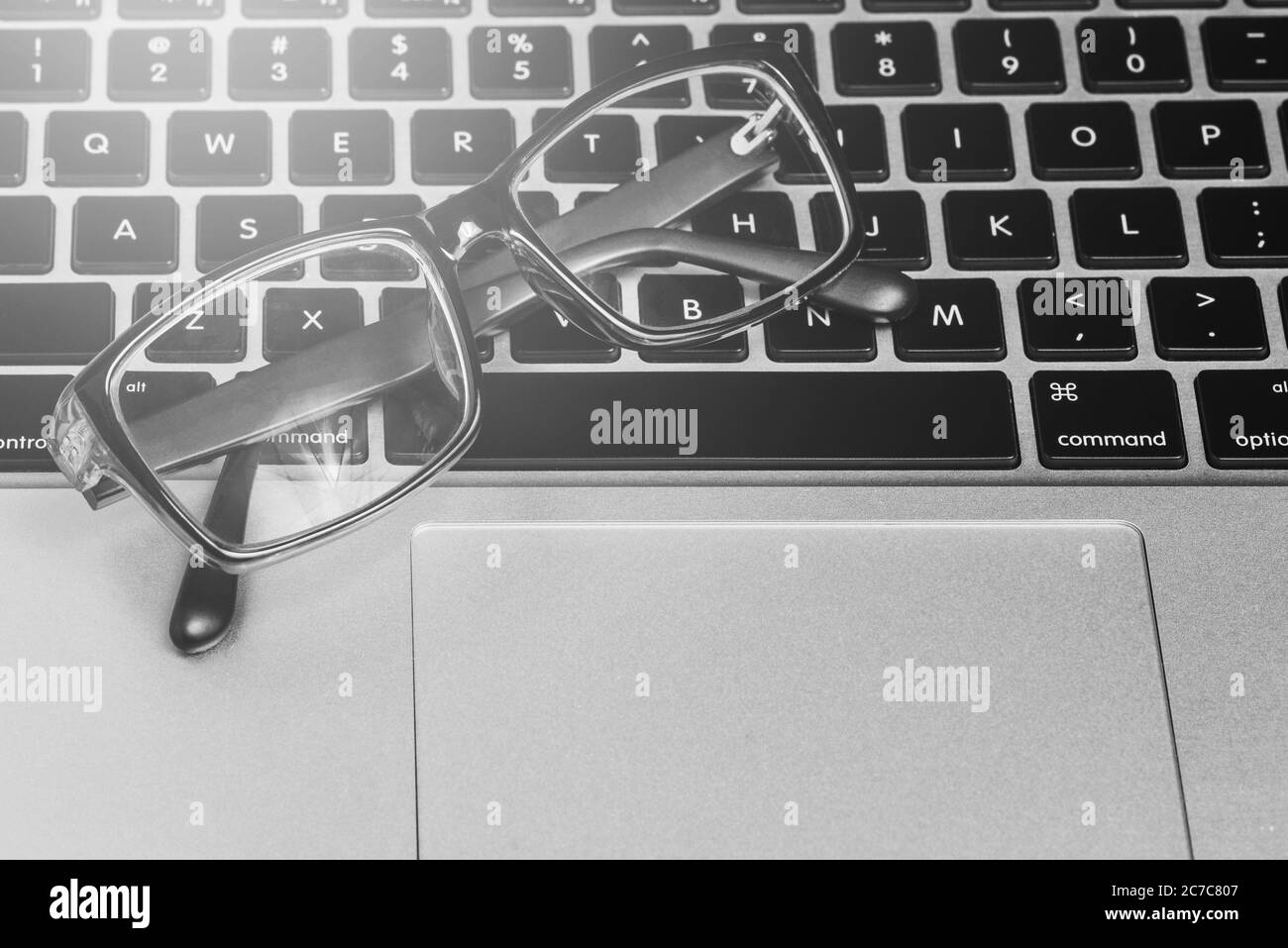 Nahaufnahme der Brille auf der Computertastatur. Laptop-Tastatur und Brille mit schwarzem Rillenumrandung. Konzept der Arbeit in einem Büro Stockfoto