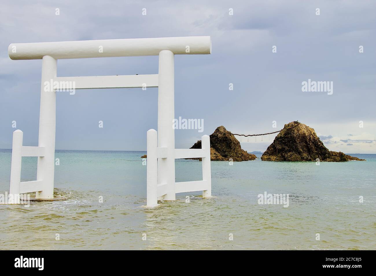 Selektive Aufnahme eines japanischen weißen Tores am Strand von Itoshima Mit Klippen im Hintergrund sichtbar Stockfoto