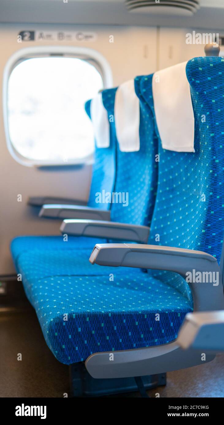 Eine Reihe von leeren Sitzen in einem Pendlerzug in Japan von Osaka nach Tokio aufgrund von Covid-19 Reisebeschränkungen weniger Passagiere, blaue Sitze, Hochgeschwindigkeitszug. Stockfoto