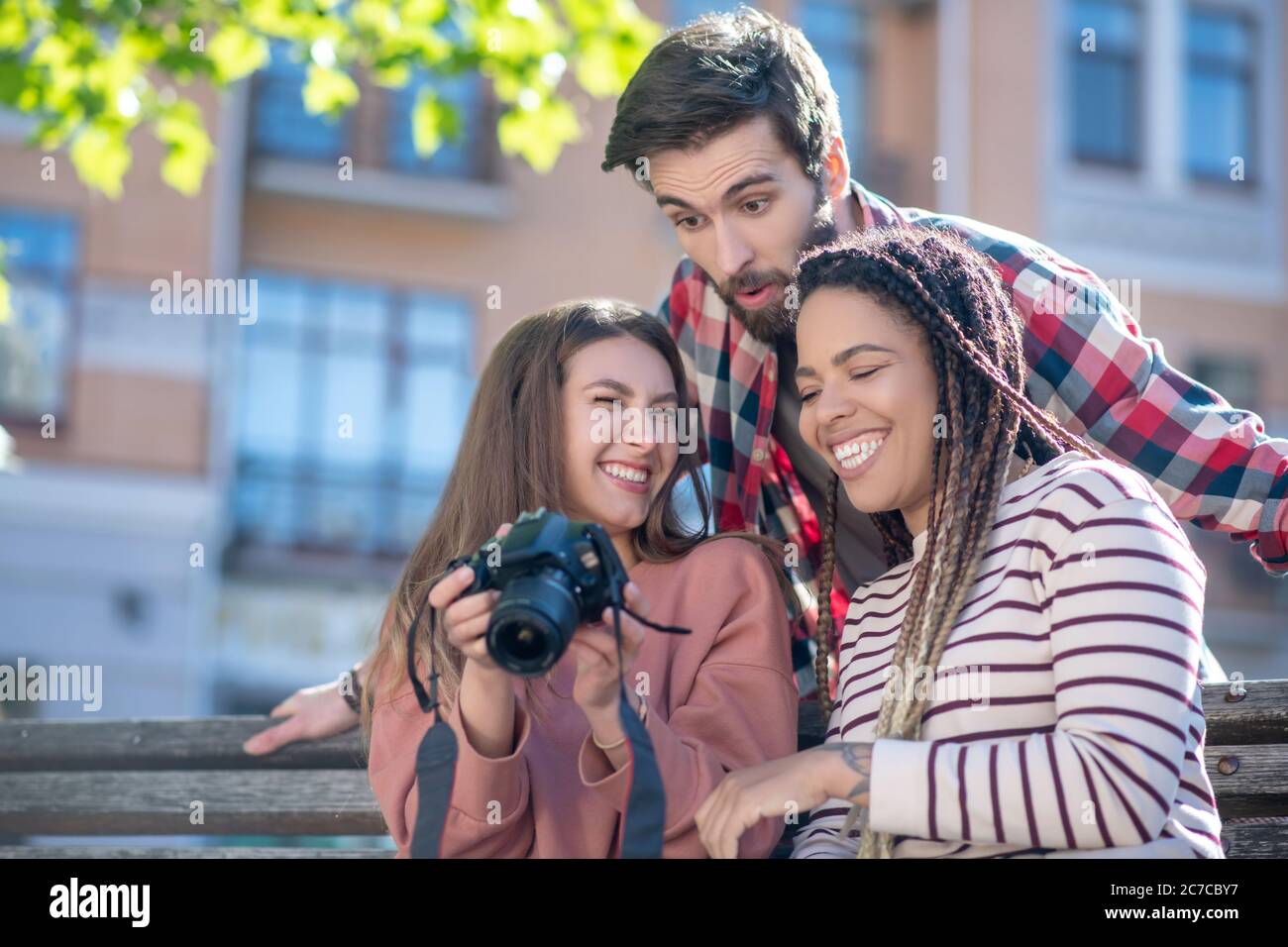 Mit Spaß Grimacing Kerl und zwei Mädchen mit Kamera Stockfoto