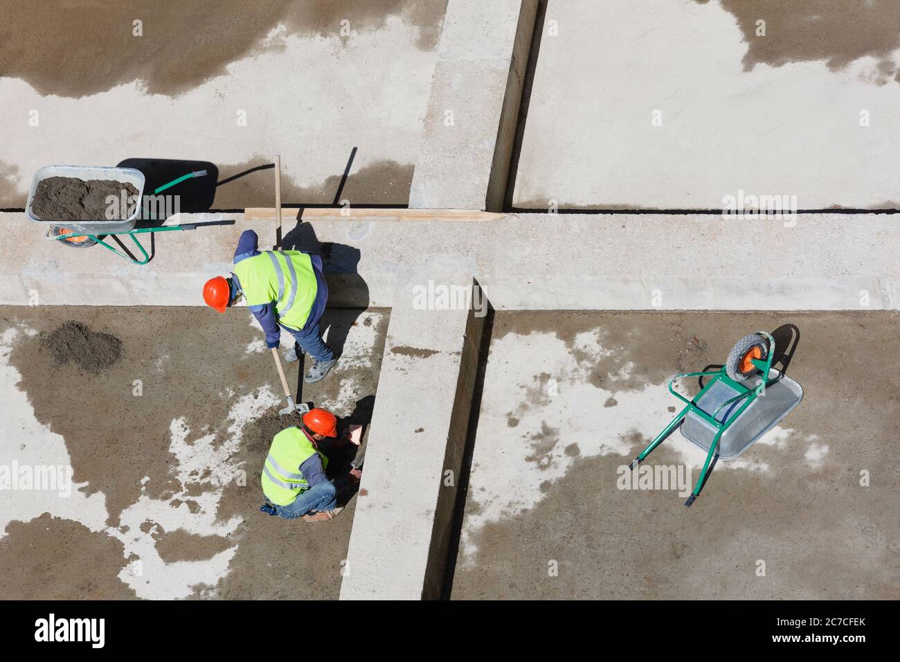 Uniformierte Mitarbeiter sauberen Sand auf einer Baustelle, Ansicht von oben. Stockfoto