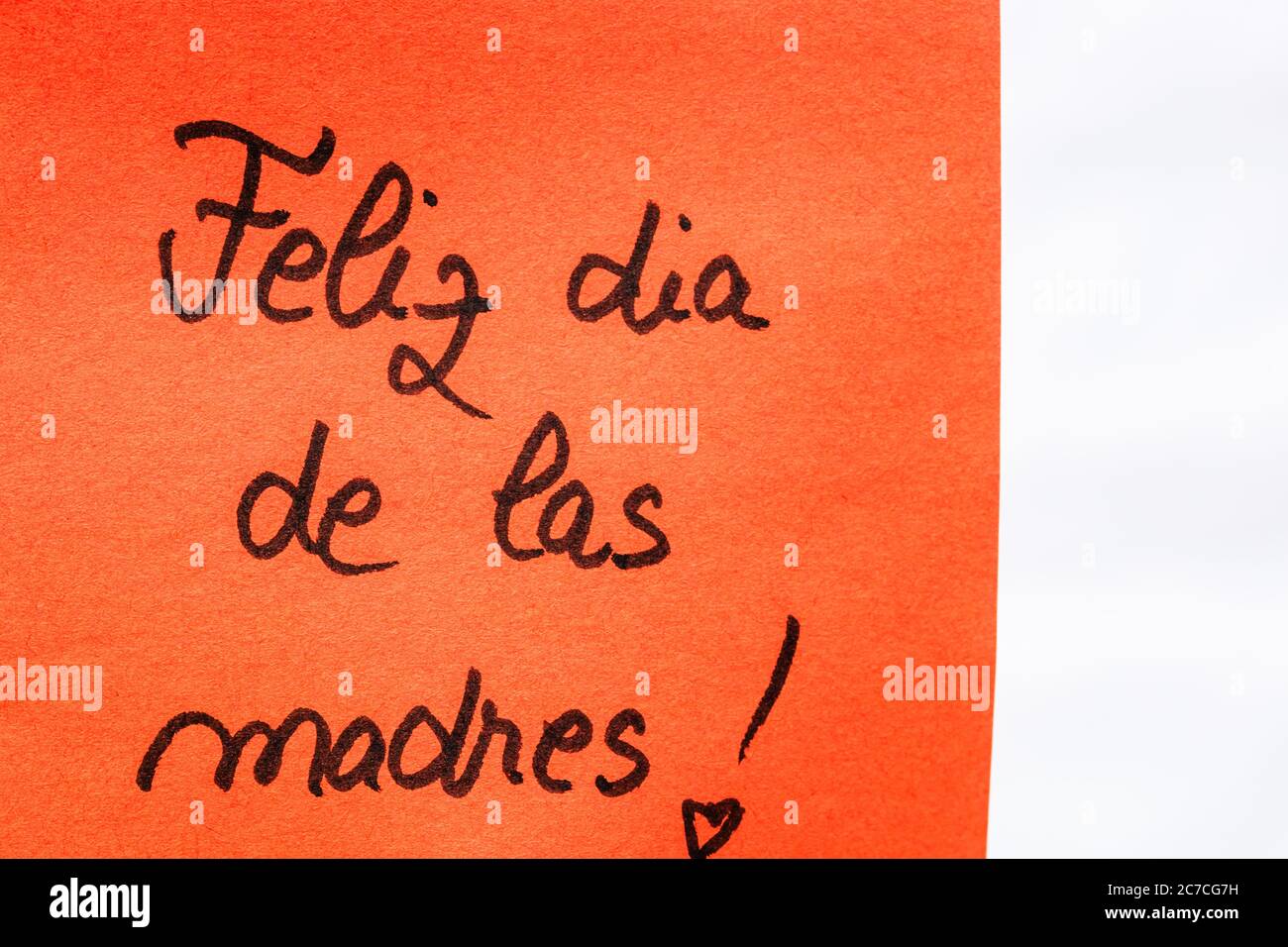 Feliz Dia de las madres (Happy day for mothers) handgeschriften Text aus nächster Nähe isoliert auf orangem Papier mit Kopierraum. Schreiben von Text auf Memo Post Erinnerung Stockfoto