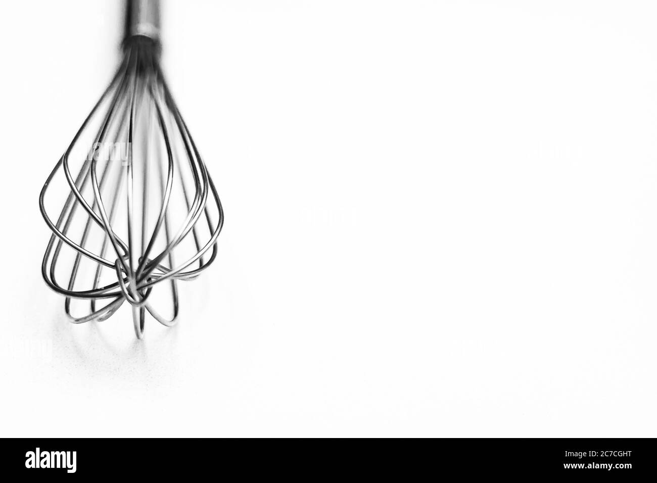 Selektive Nahaufnahme Graustufen Aufnahme von Whisks auf weißem Hintergrund Stockfoto