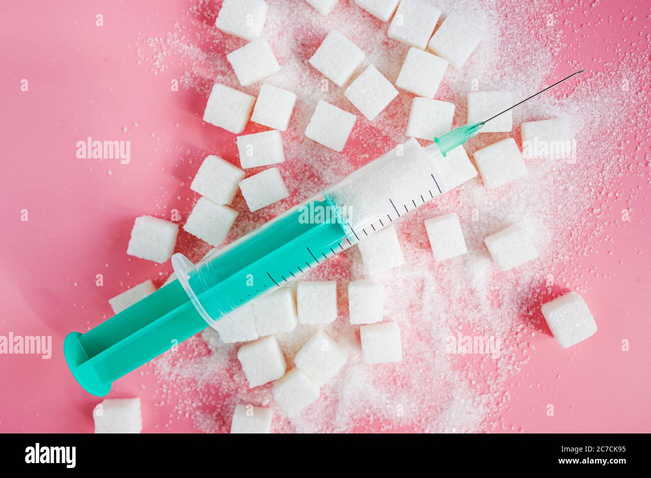Granulatzucker, Zuckerwürfel und Spritze auf rosa Backgroud. Stockfoto