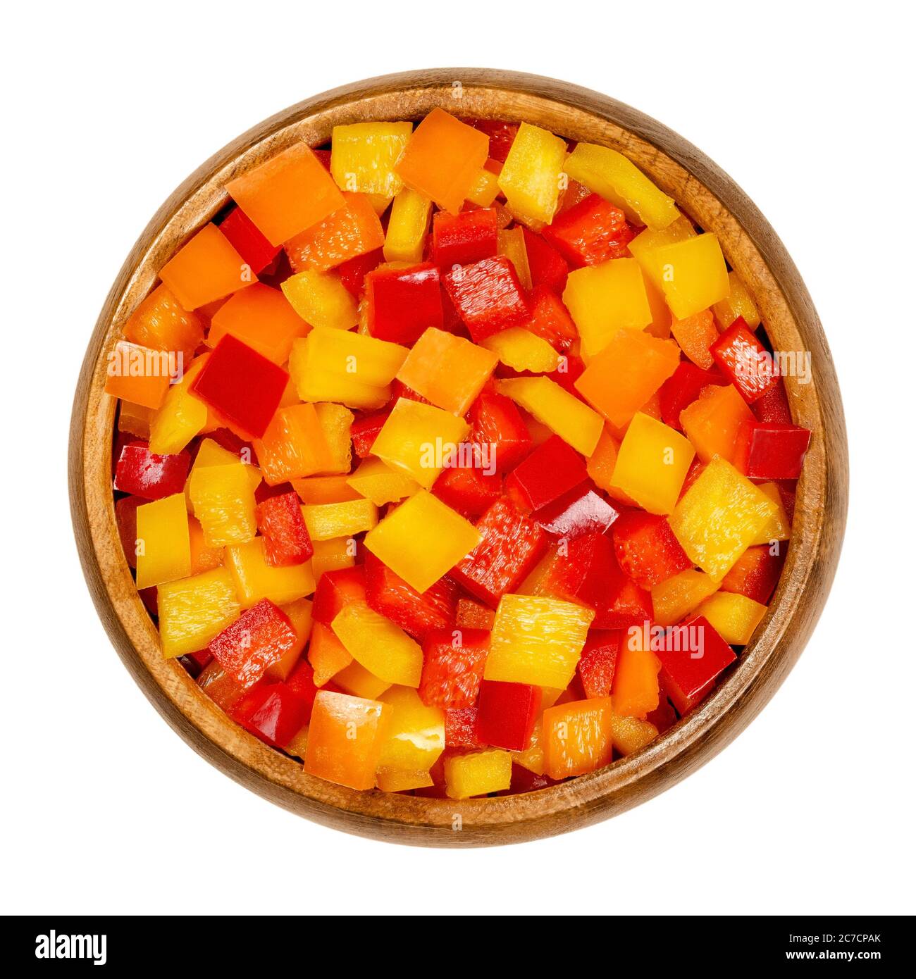 Paprika in Würfel geschnitten in einer Holzschüssel. Paprika, Paprika oder auch Paprika genannt, in bunte Chips geschnitten. Frische gelbe, orange und rote Früchte. Stockfoto