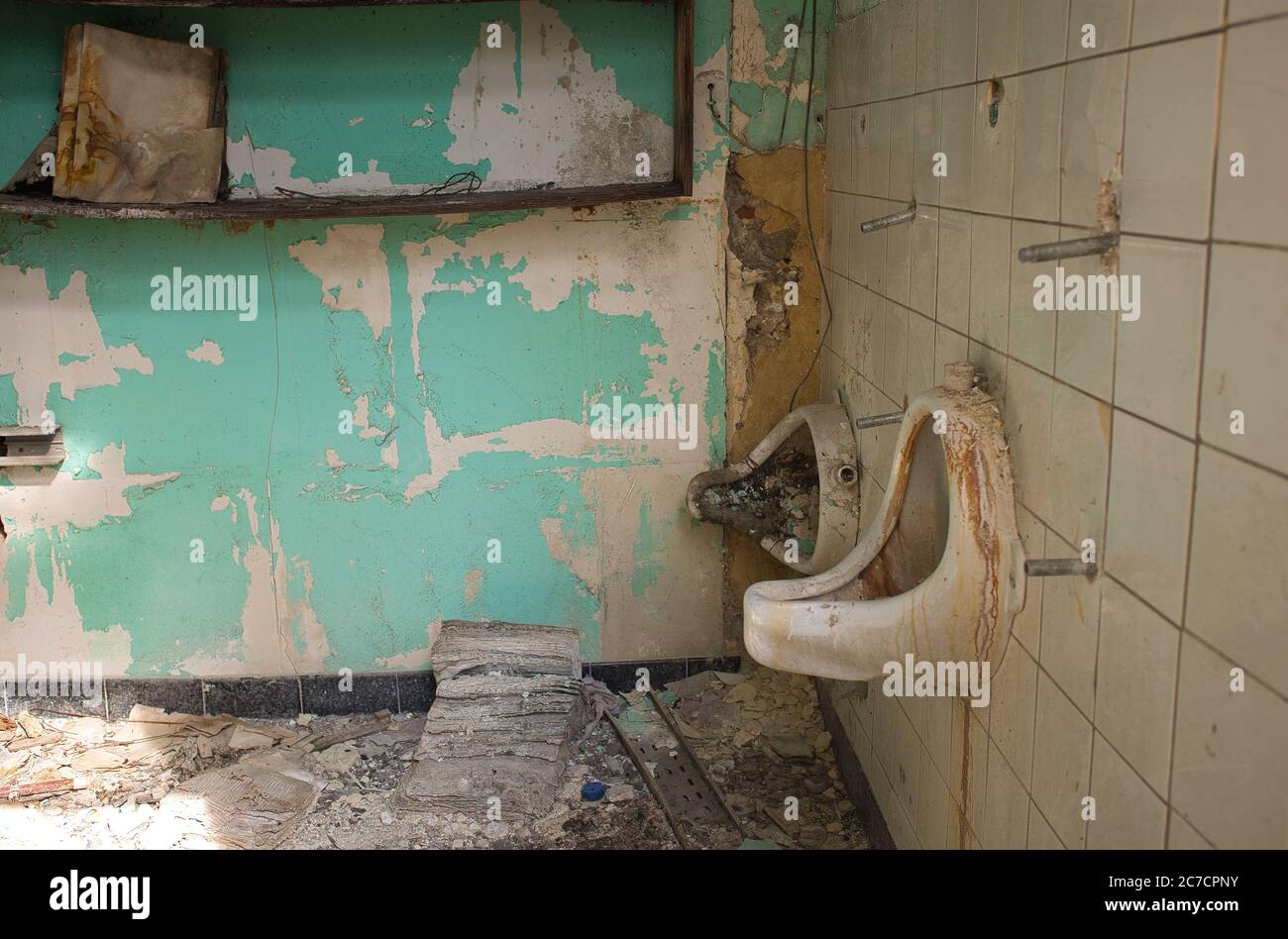 Horizontale Aufnahme einer alten zerstörten öffentlichen Toilette mit weißen Fliesen in Drogenbos, Belgien Stockfoto