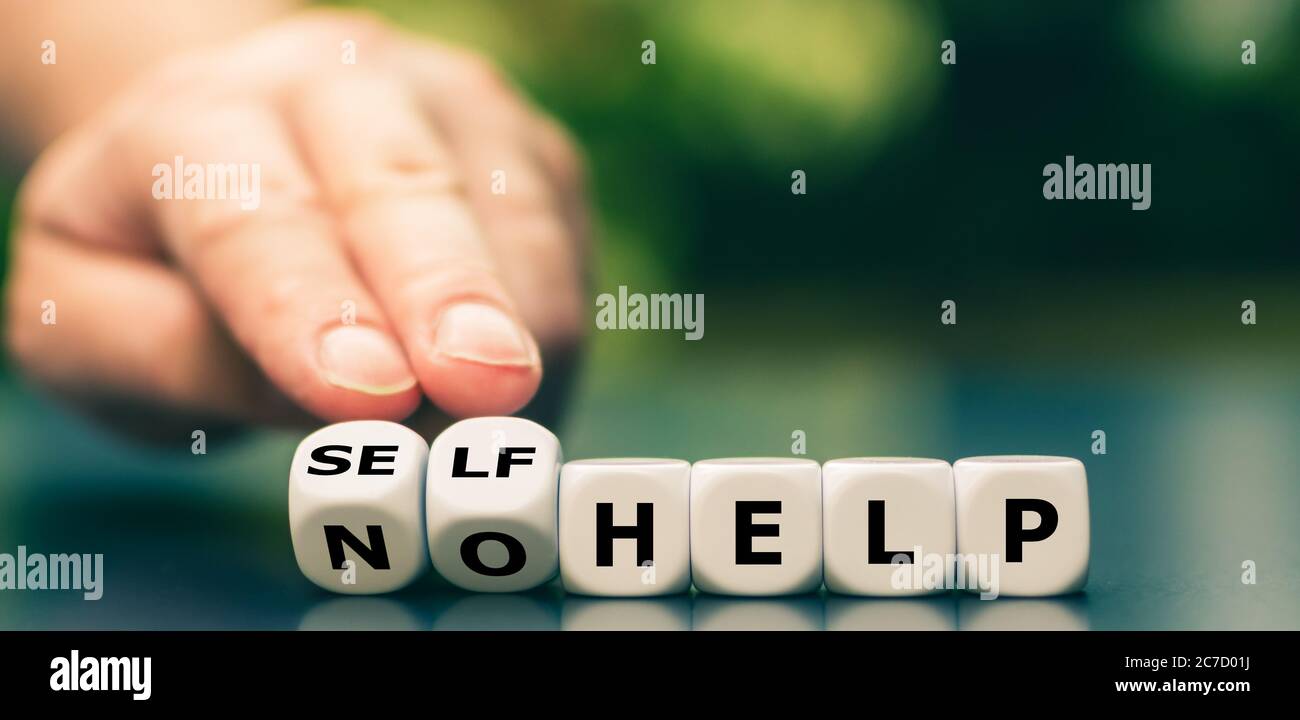 Hand dreht Würfel und ändert den Ausdruck "keine Hilfe" in "Selbsthilfe". Stockfoto