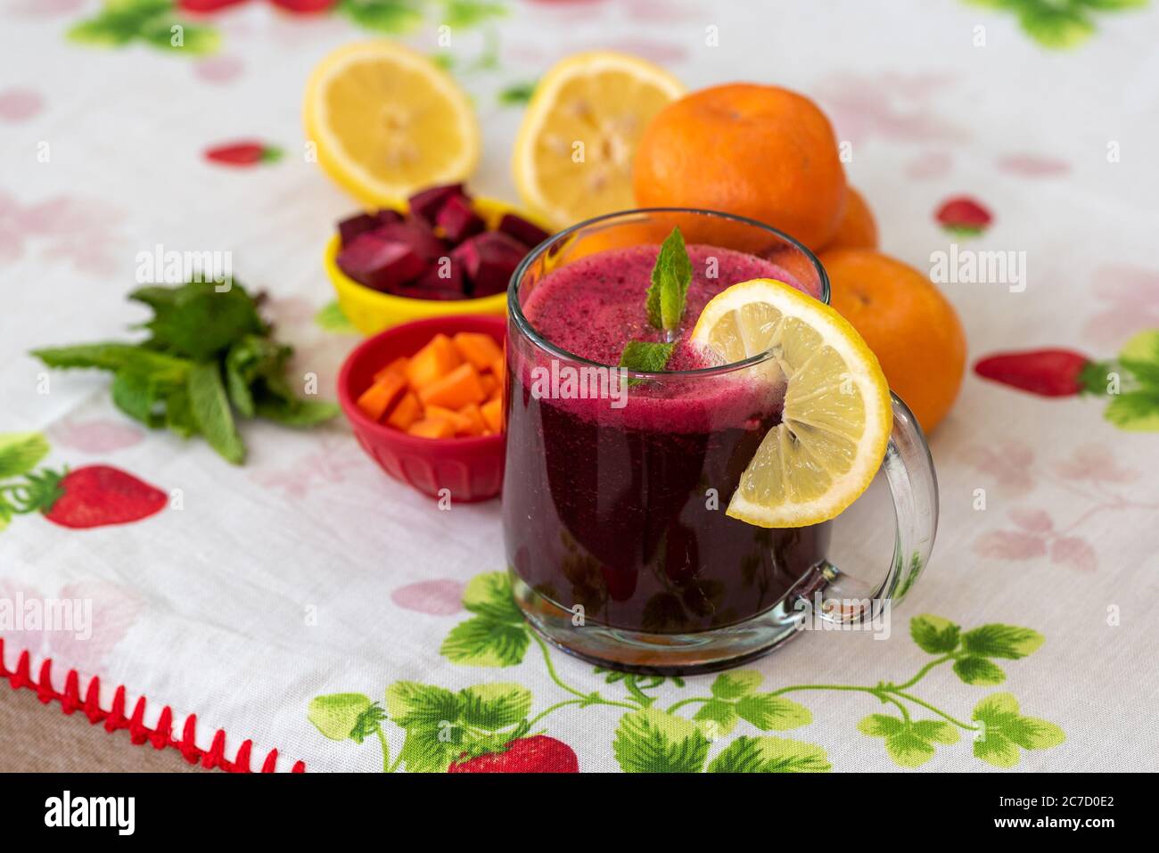 Bunte Stillleben porträtiert einen Saft aus Früchten und Wurzeln über Tischdecke mit bunten Designs dekoriert Stockfoto
