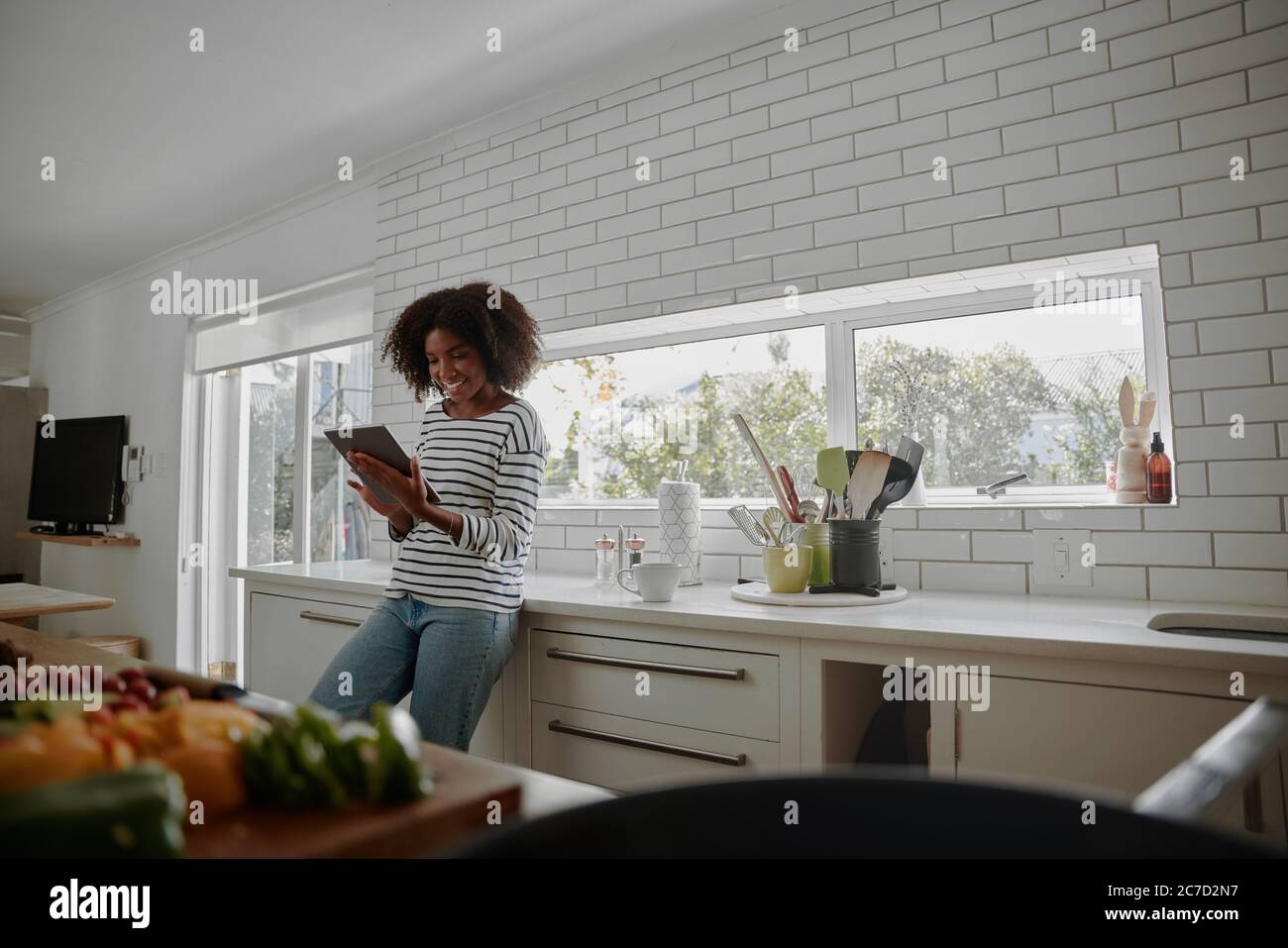 Schöne Frau Browsing Tablet für Rezept in der Küche zu Hause Stockfoto