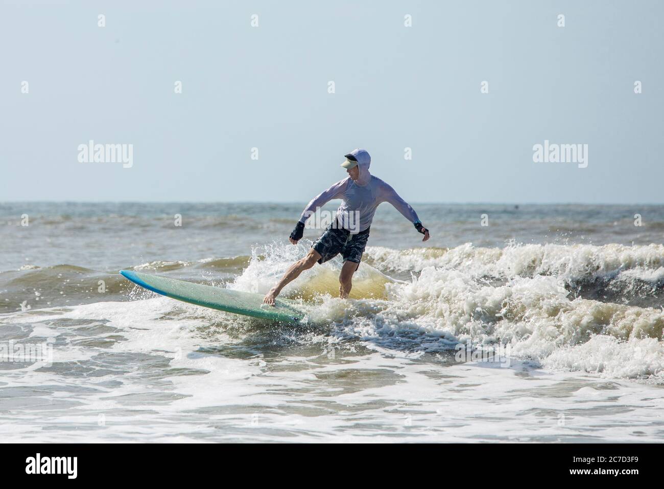 Mann mittleren Alters auf einem langen Brett im Atlantik surfen. Stockfoto