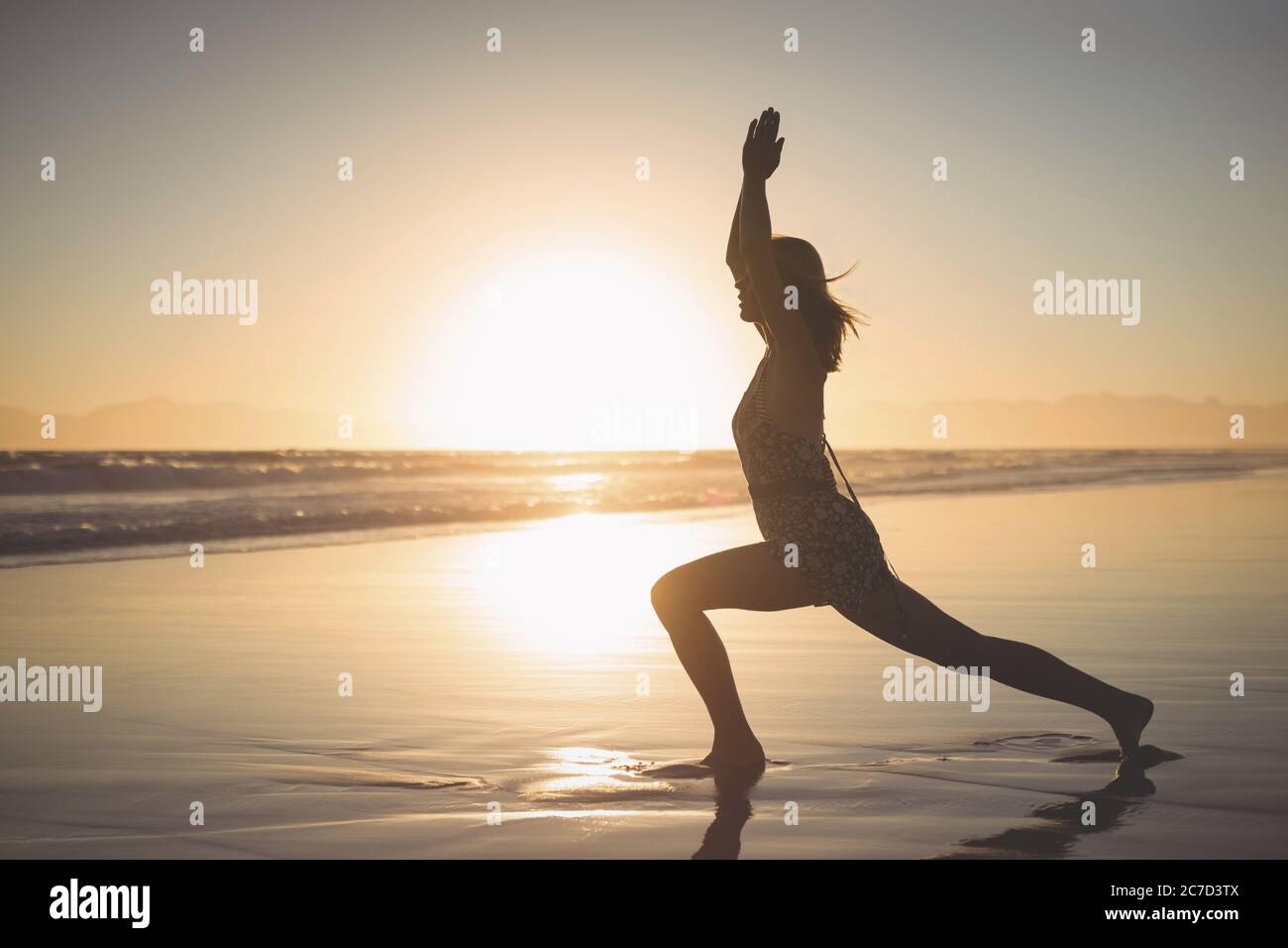 Frau spielen Yoga-Sonnengruß mit Sonnenaufgang Hintergrundbeleuchtung am Strand Stockfoto