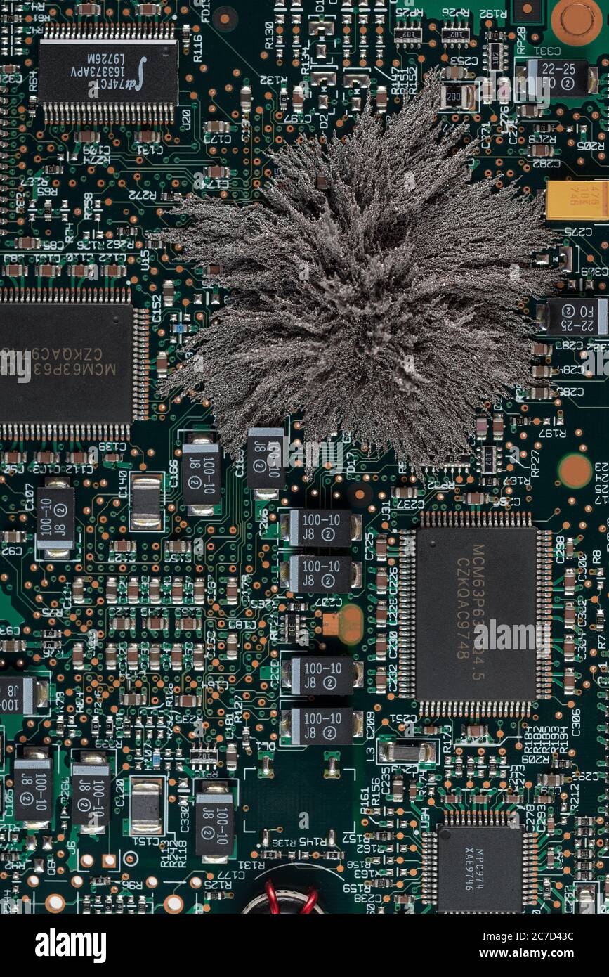 Magnetfelder, die durch Mac-Computer-PC-Boards passieren, wo Eisenspäne unsichtbare Feldlinien zeigen, die von einem einzigen Pol permanentem Neodym kommen Stockfoto