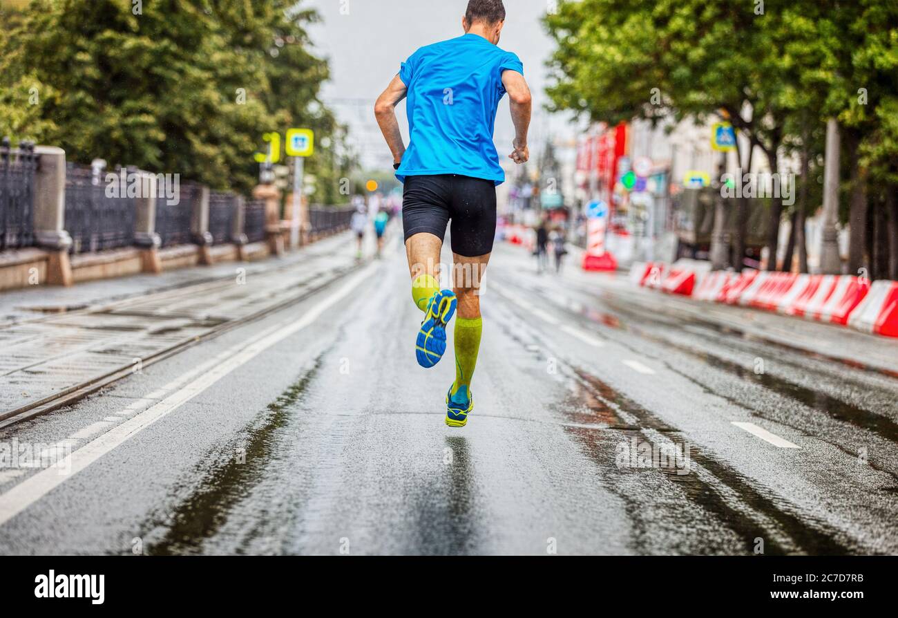 Back man Athlet läuft Marathon auf der Straße bei regnerischem Wetter Stockfoto