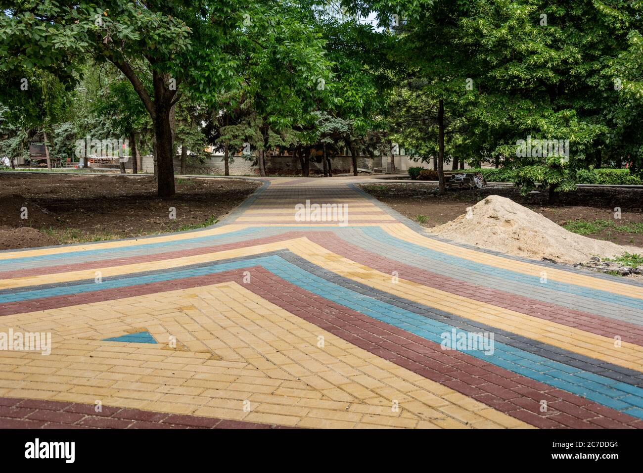 Verlegung von farbigen Betonplatten im Park. Professionelle Arbeiter Maurer installieren neue Fliesen und Pflasterplatten für Bürgersteig auf Ebenen s Stockfoto