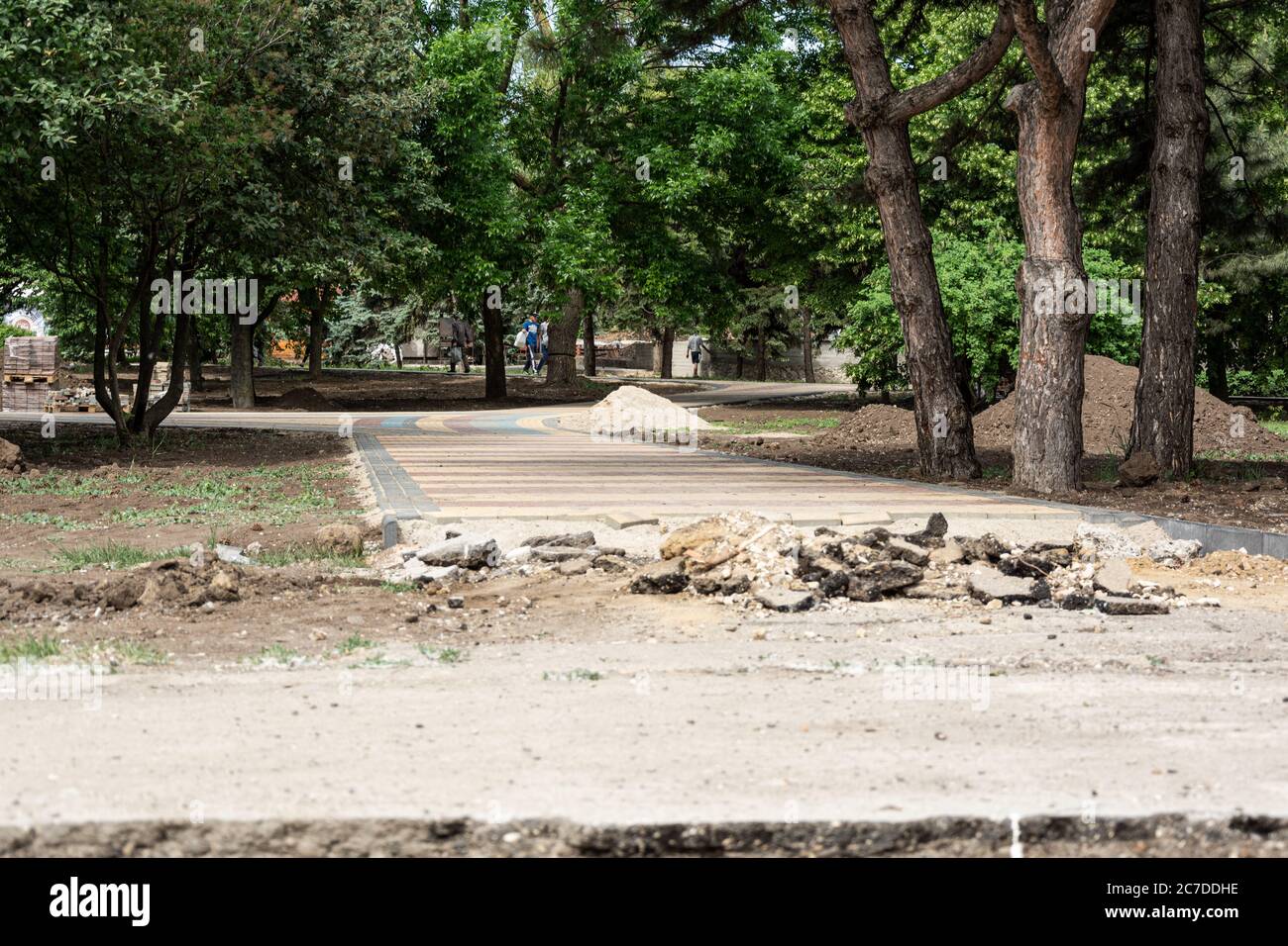 Verlegung von farbigen Betonplatten im Park. Professionelle Arbeiter Maurer installieren neue Fliesen und Pflasterplatten für Bürgersteig auf Ebenen s Stockfoto