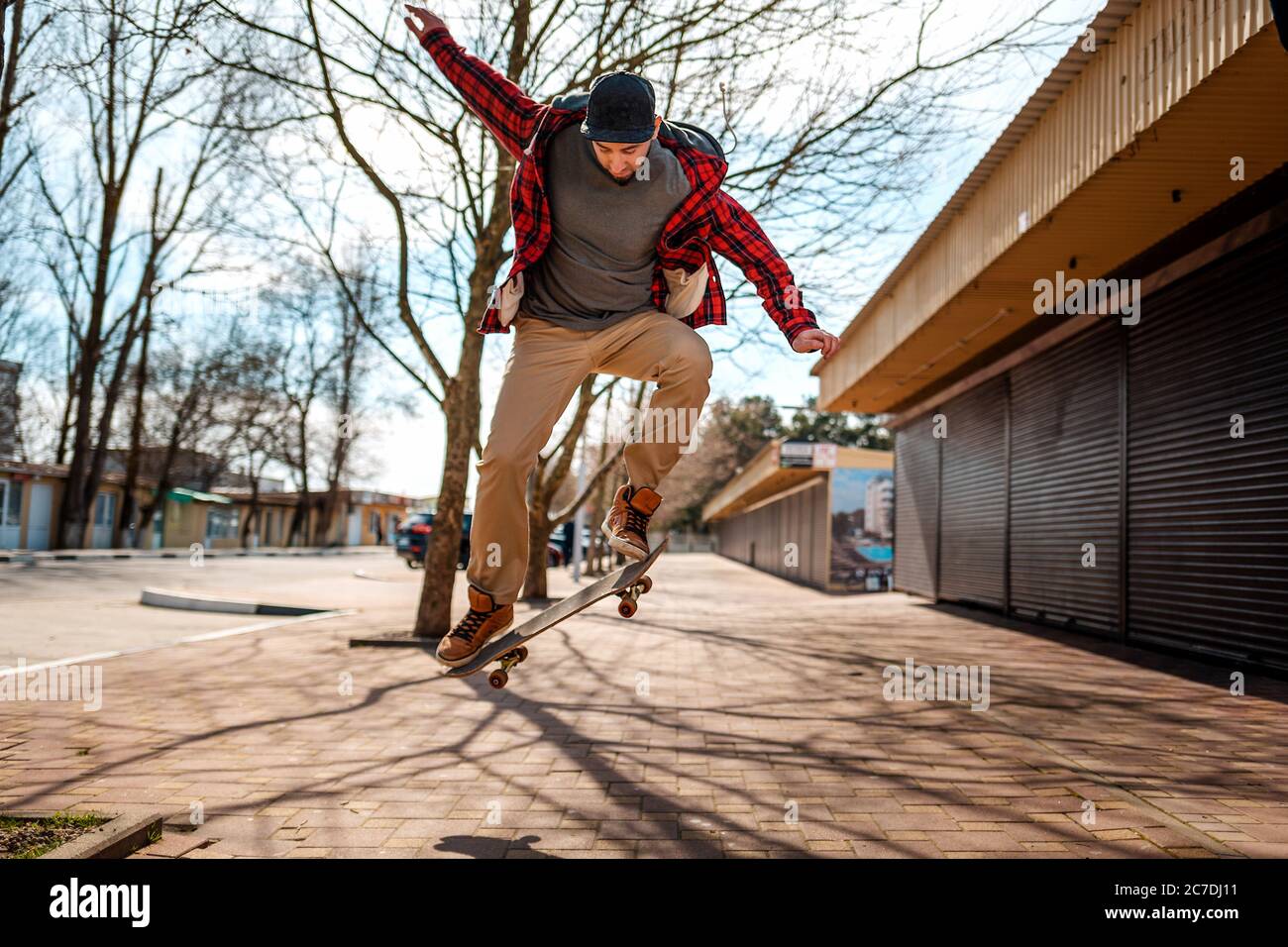 Ein junger Hipster-Mann macht einen Sprung mit einem Skateboard, Kickflip oder Ollie. Speicherplatz kopieren. Konzept des aktiven Lebensstils und der Straßenkultur. Stockfoto